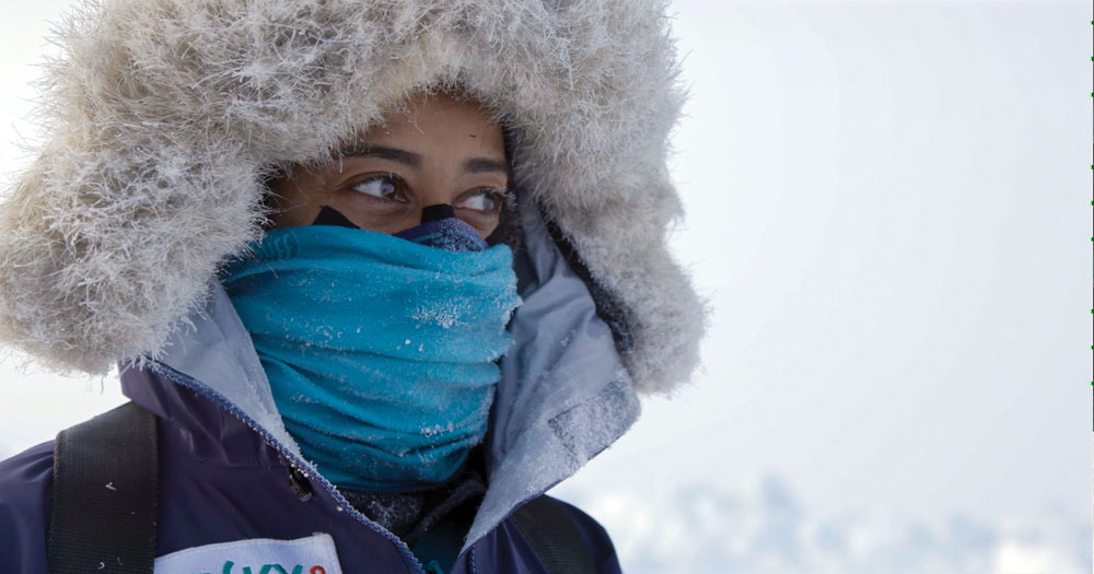 Filmstill from Exposure of a woman in a fur hood with a blue neck gaiter over her face