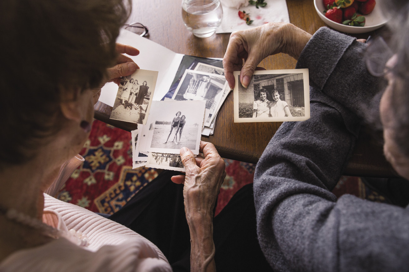 photos scattered on a table as 2 women look at them