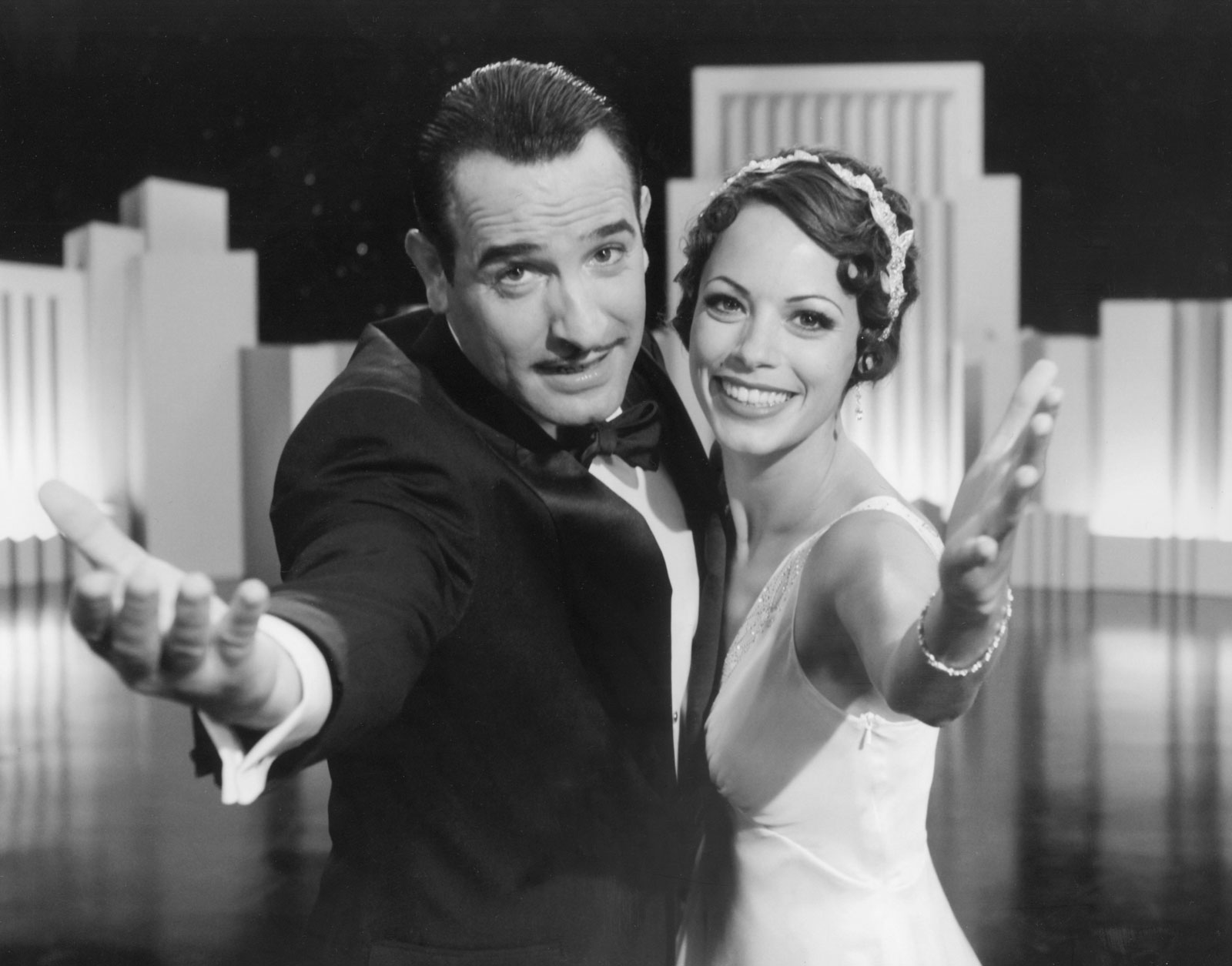 a man and woman embrace and with outside arms outstretched 