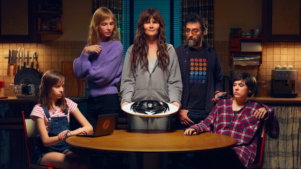 A family stands around a woman serving a black crab on a plate