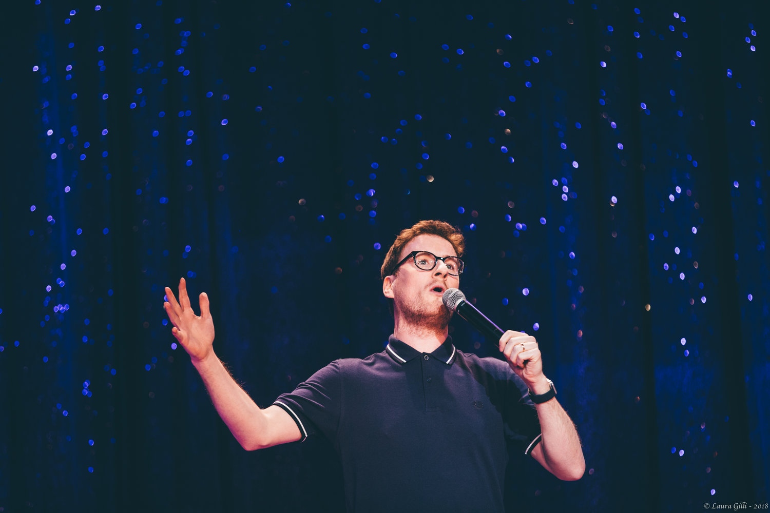 A man with glasses speaking into a microphone