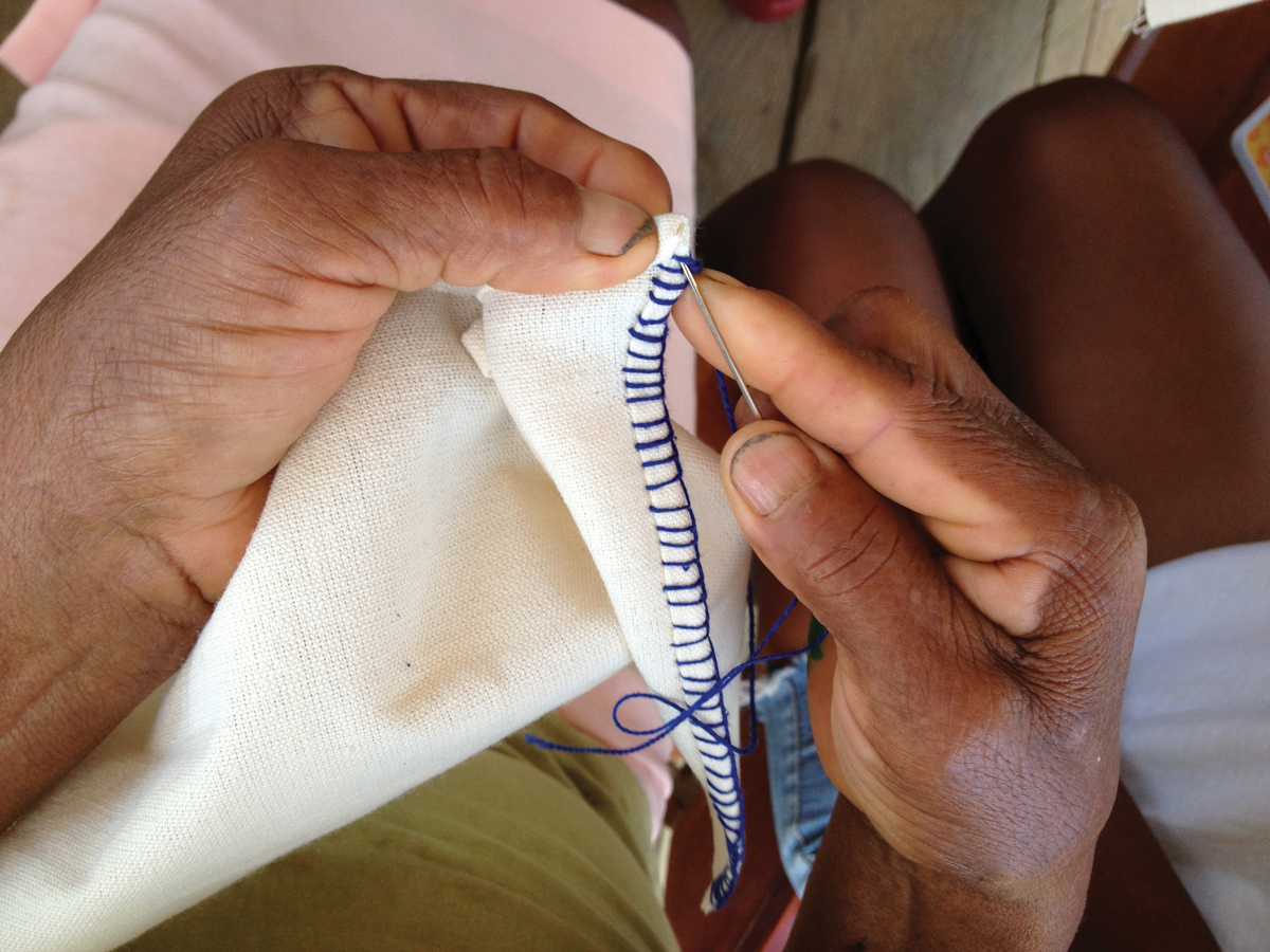 A hand sewing a story cloth