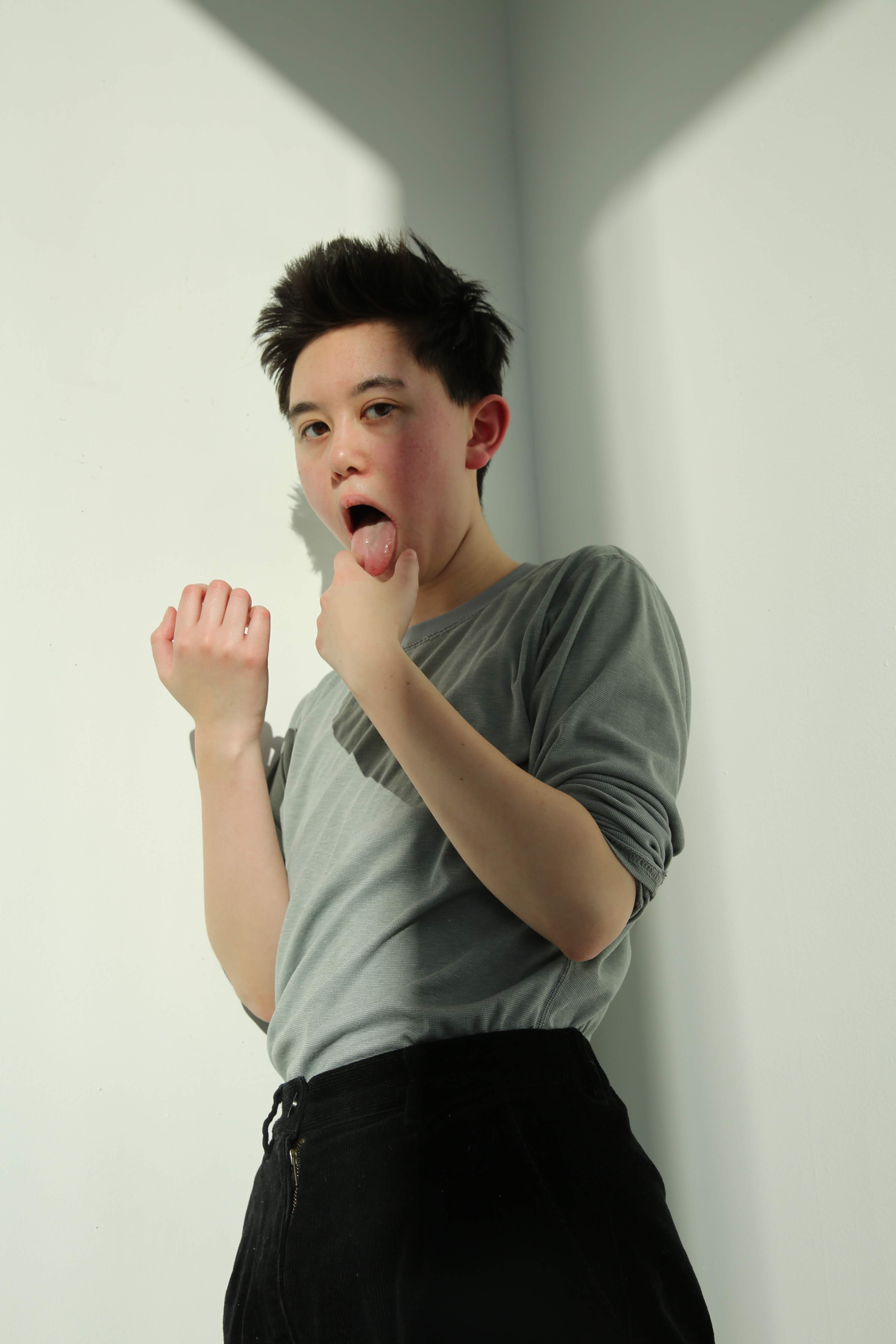 upper body photo of Noa Rui-Piin Weiss with his tongue out as he leans against a wall