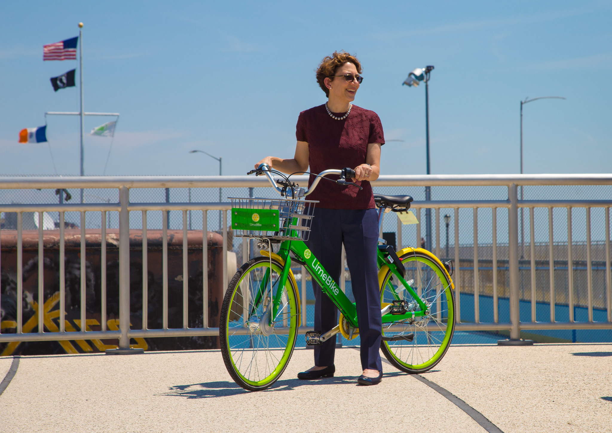 Polly Trottenberg stands over a green bikeshare bicycle on a pier in New York City