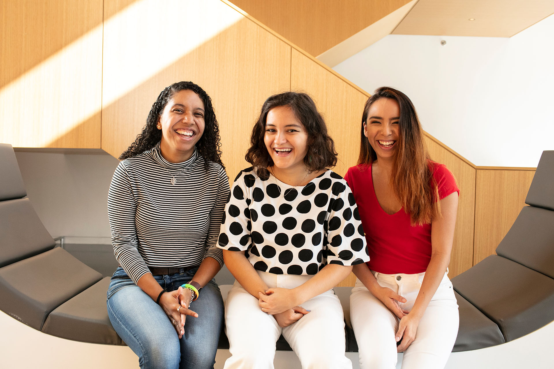 3 students smiling on bench in library