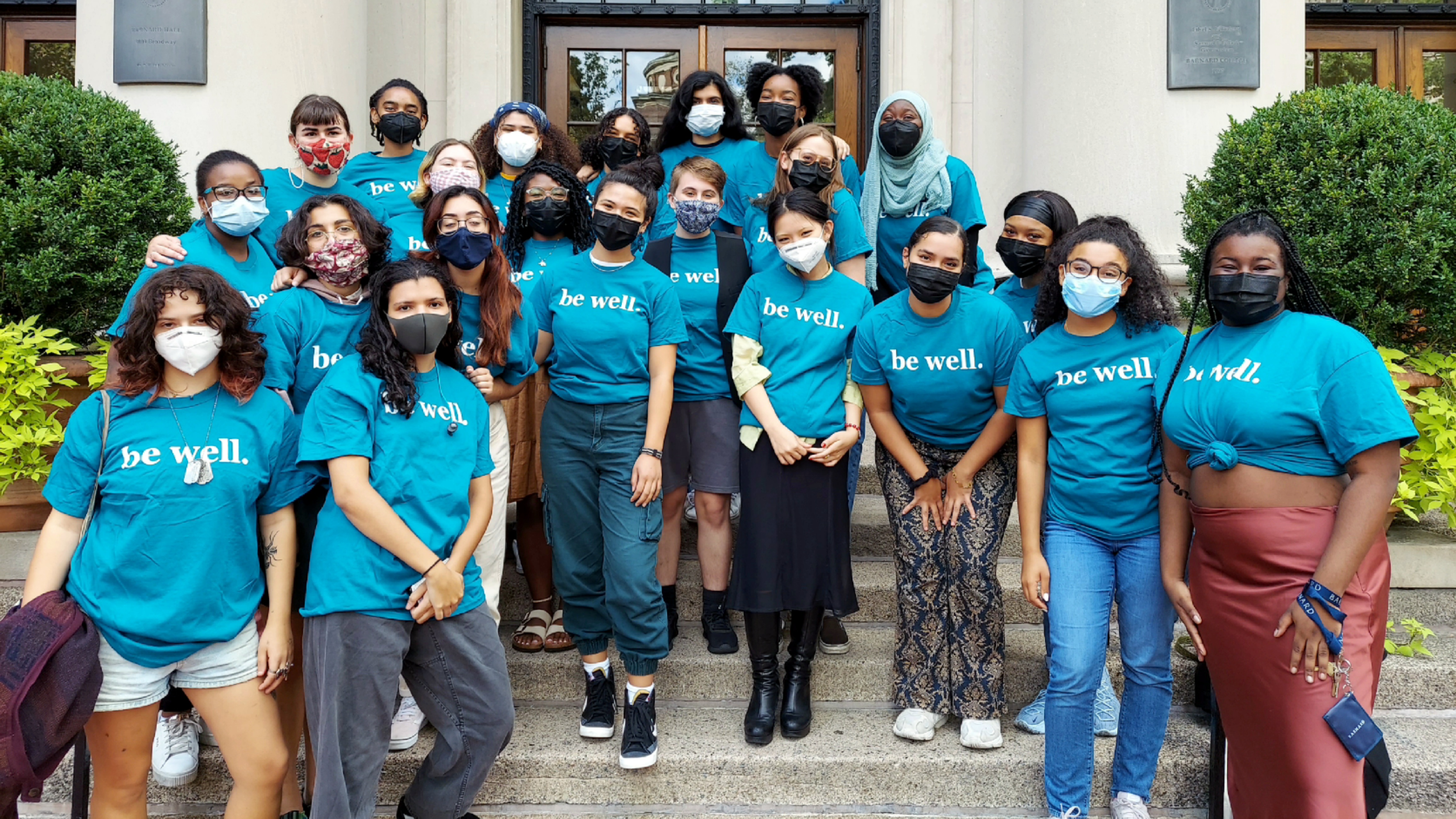 The 2021 / 2022 peer educators stand on the steps of Barnard hall. They are wearing blue shirts and masks.