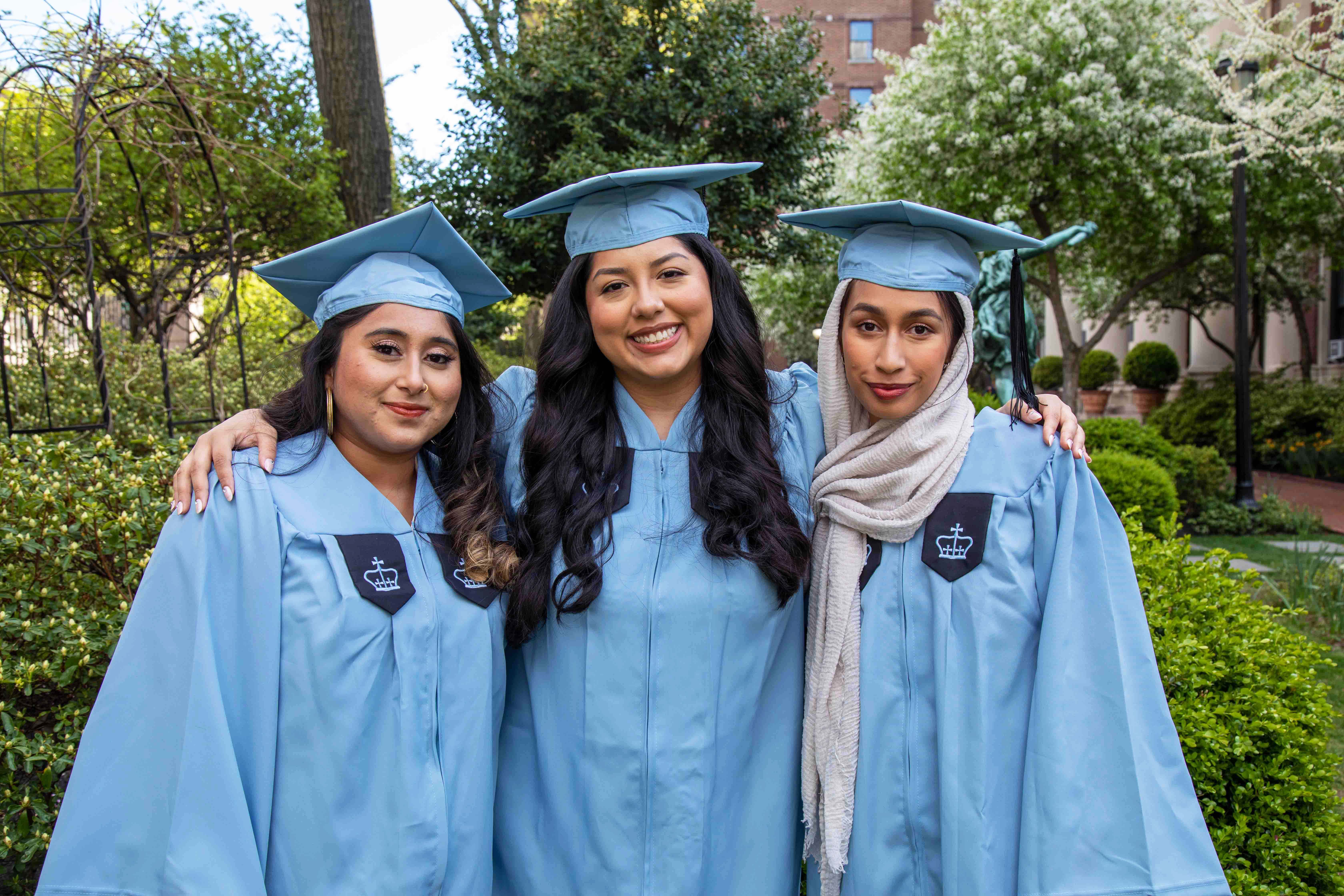  Samantha Bhuiyan ’22, Stephanie Secaira ’22, and Amana Mohiuddin ’22 pose together in their cap and gown ensembles.