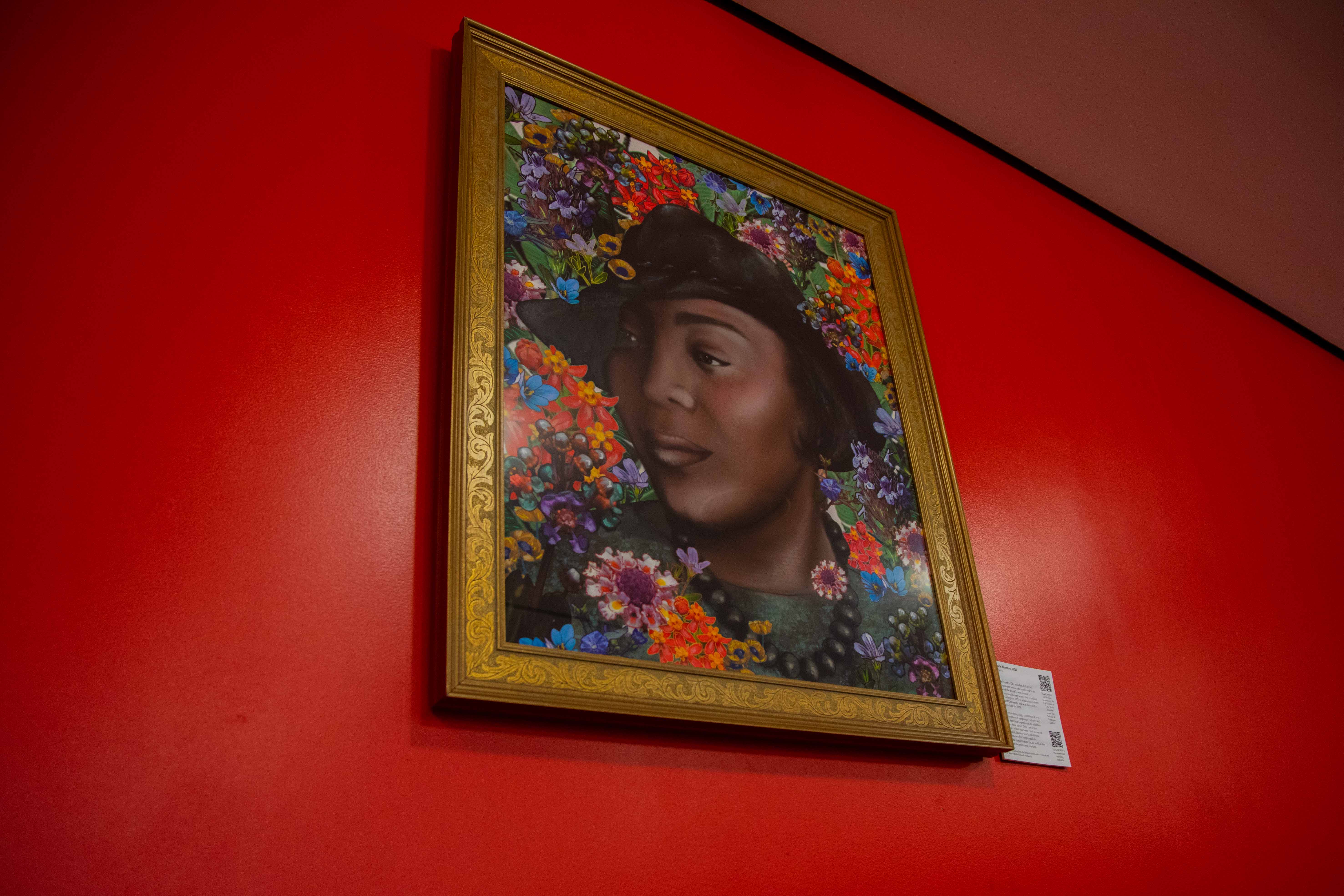 Zora Neale Hurston portrait hanging on red wall in Diana Center lower level.