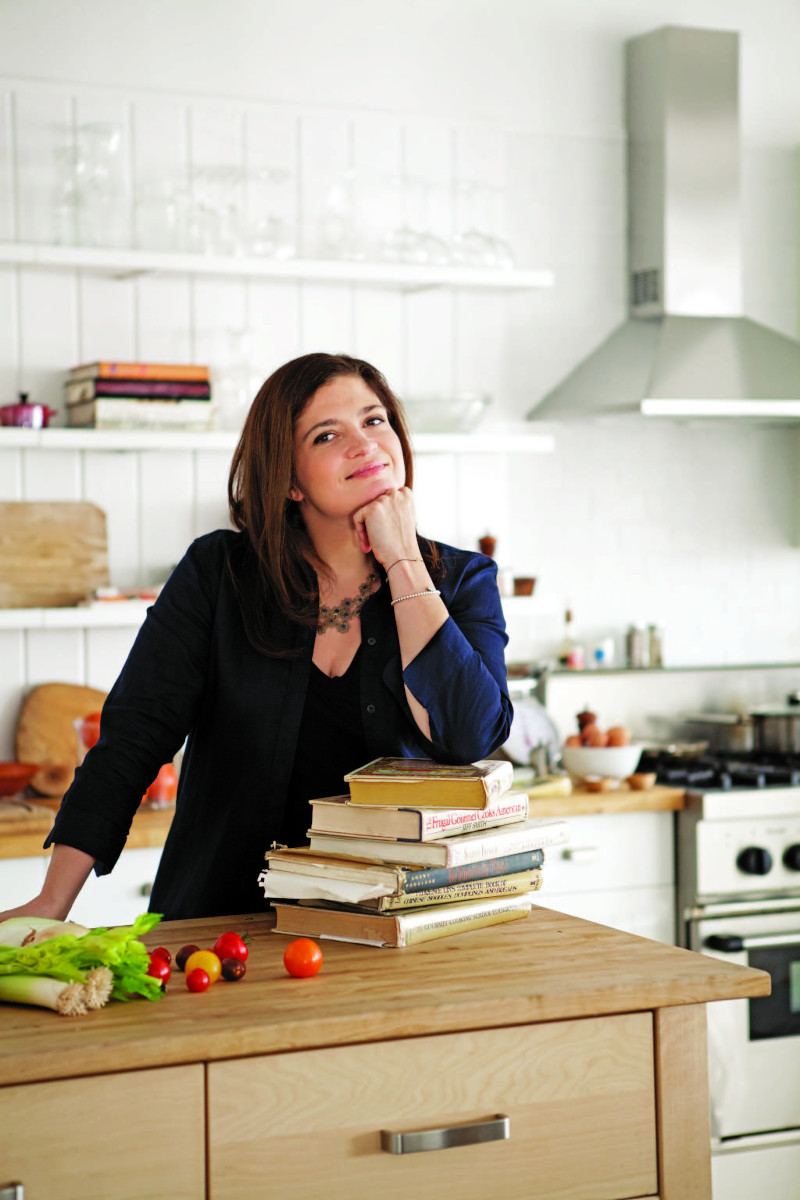 Alex Guarnaschelli with elbow resting on cook books