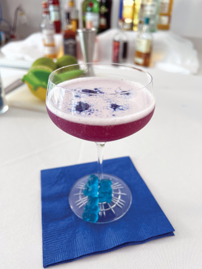 purple cocktail sitting in stemmed glass on blue napkin