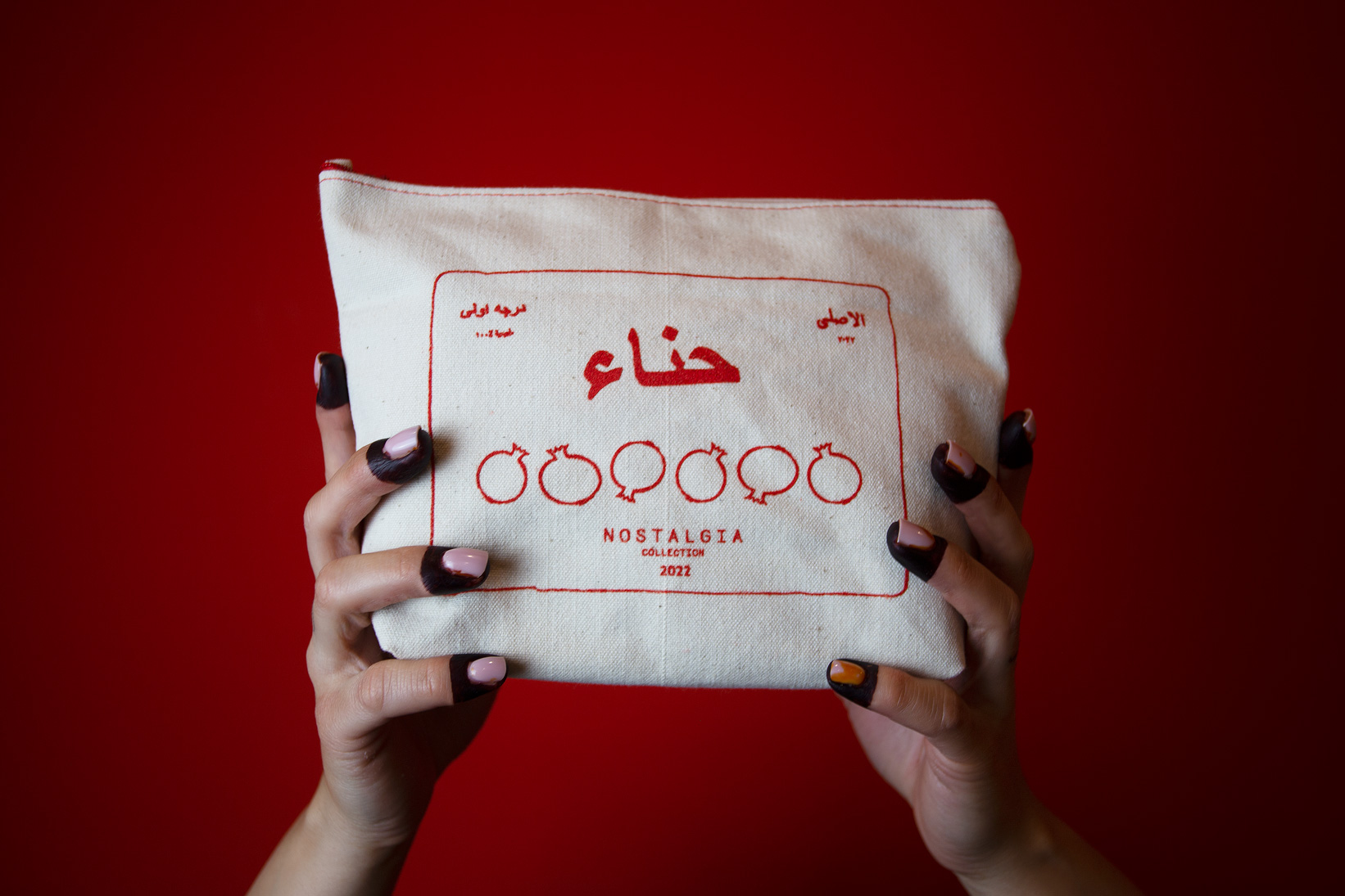 Red background and henna hands holding up a white pouch