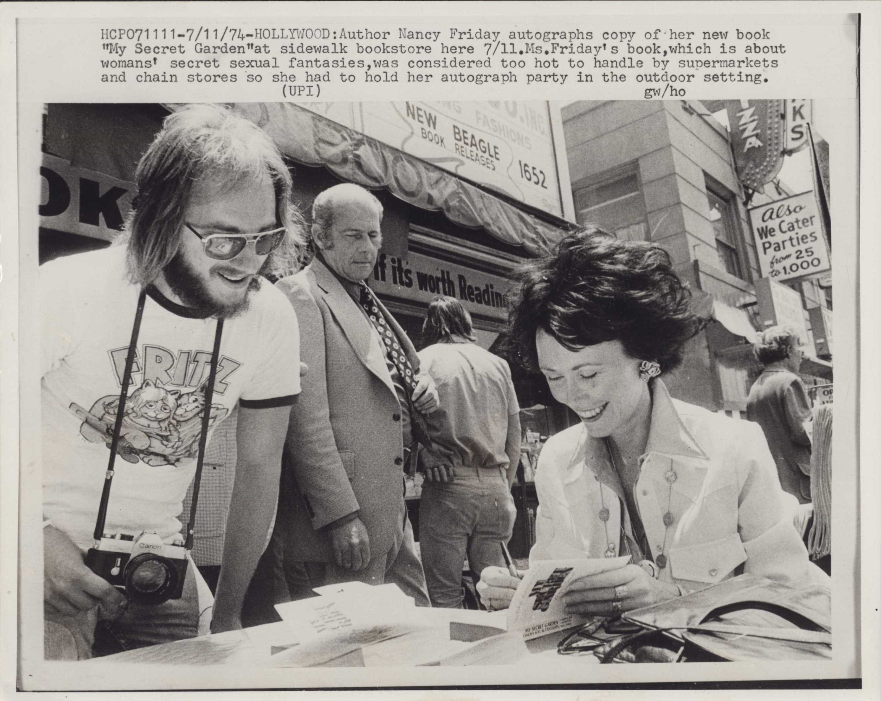 Nancy Friday sits outside signing a book