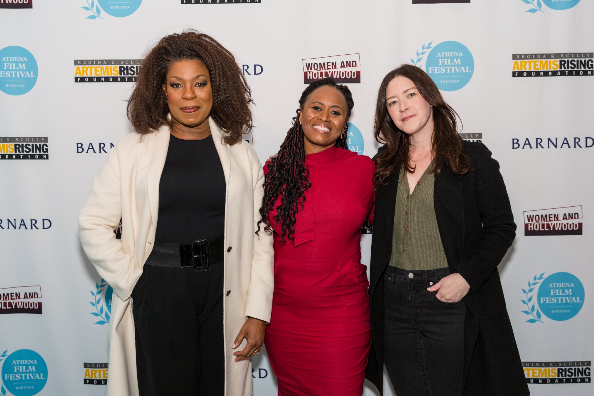 A group of smiling filmmakers and supporters in front of the 2022 Athena Film Festival step and repeat banner