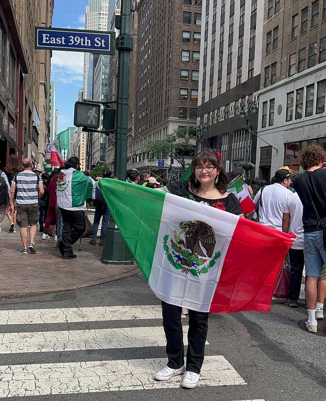 Ariana Banez ’27 on NYC street holding large Mexican flag