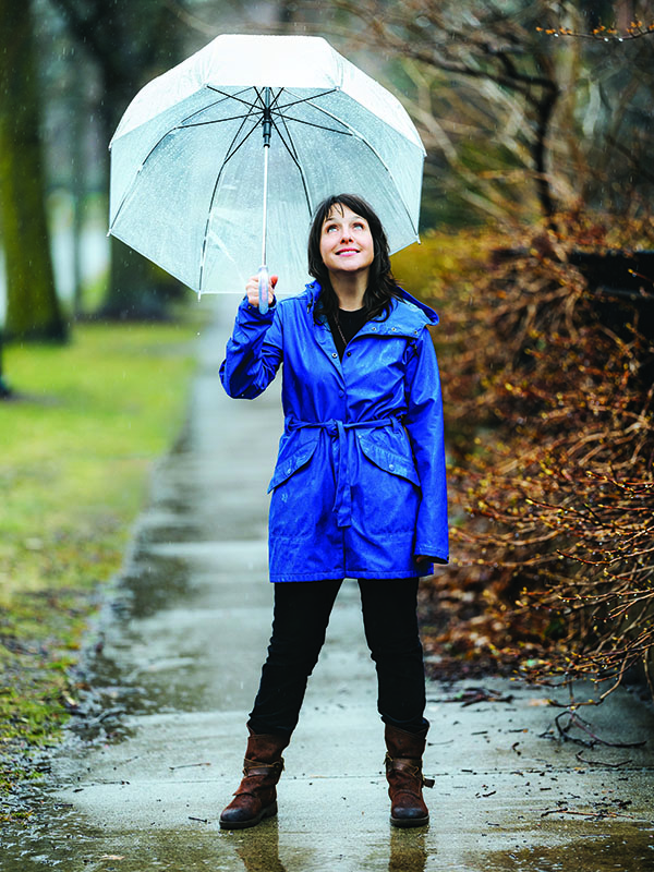 Sarah B. Miller stands in rain with umbrella