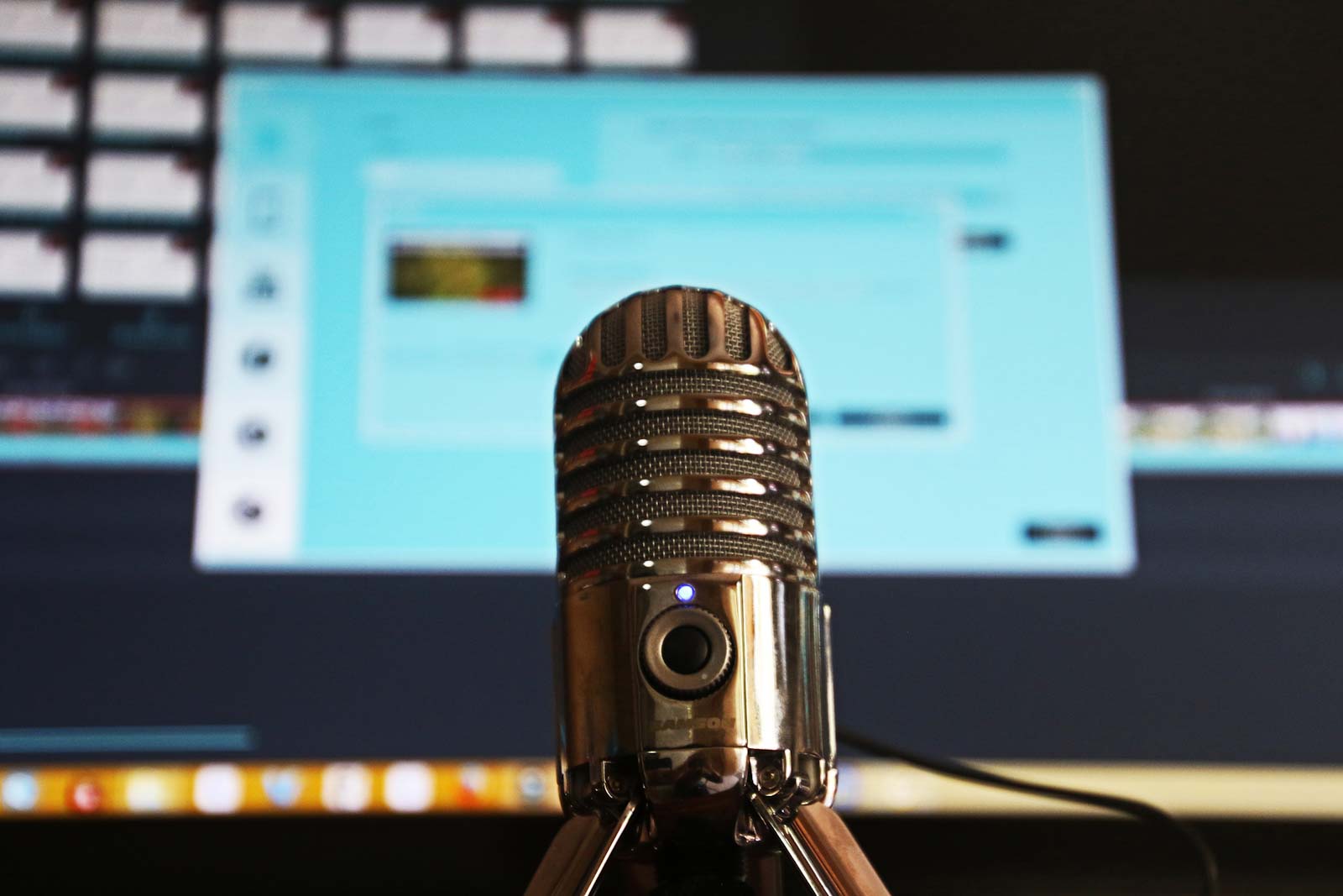 desktop microphone in close up, in front of a large computer screen