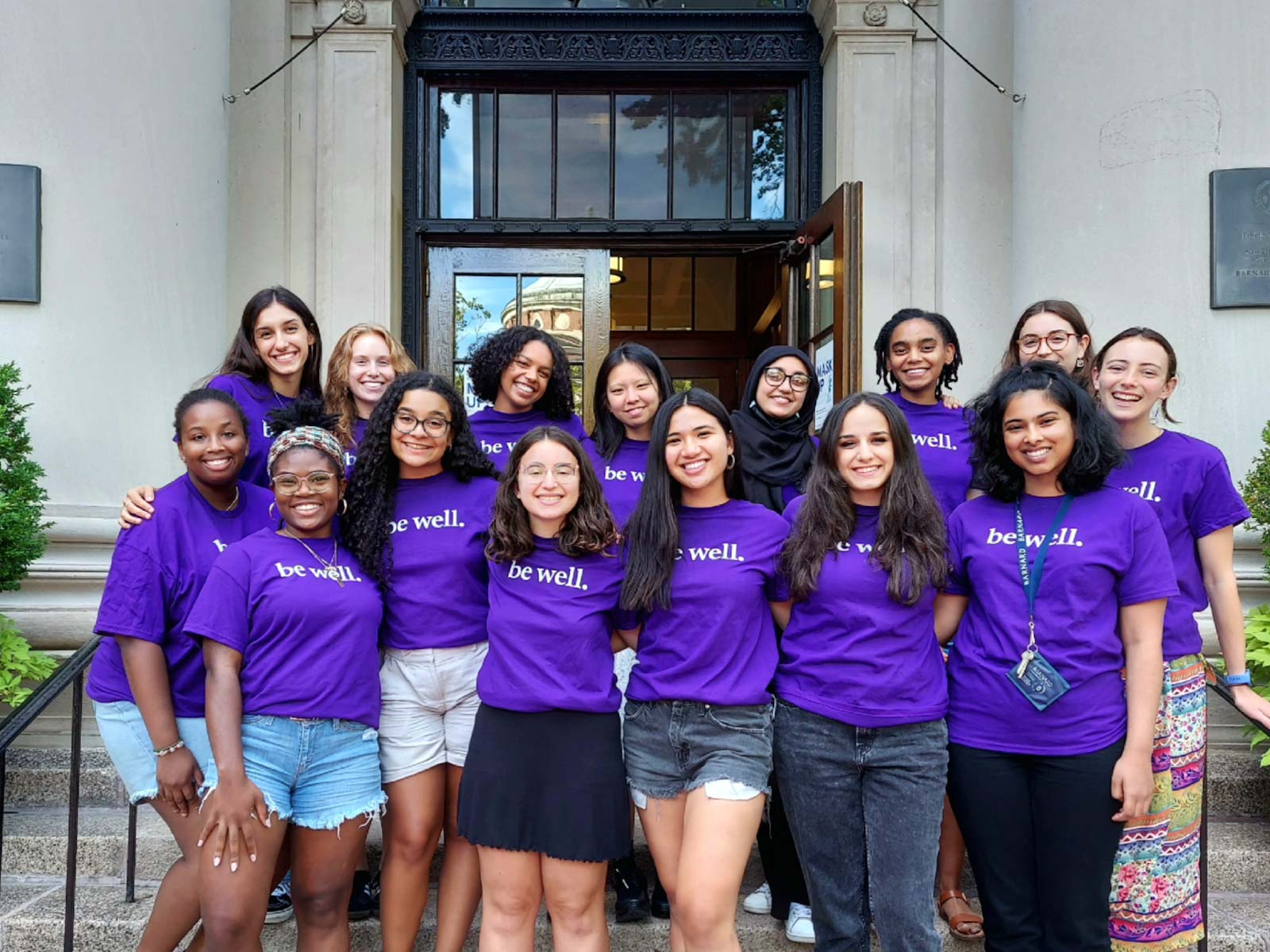 Wellness Spot peer educators stand on the steps of Barnard Hall wearing purple