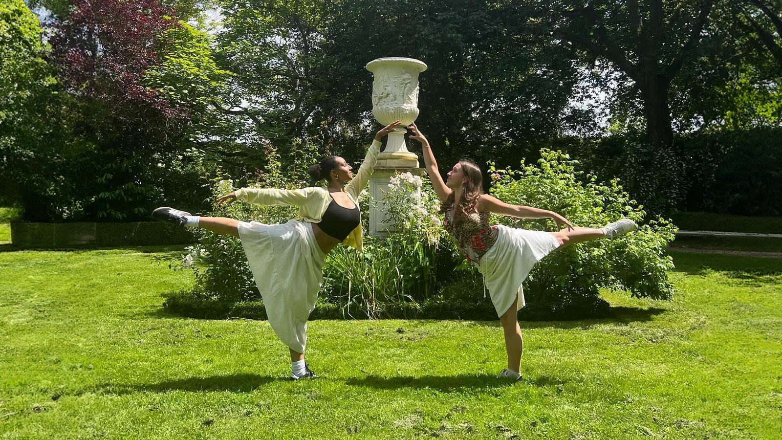 Two dancers post in garden in front of fountain