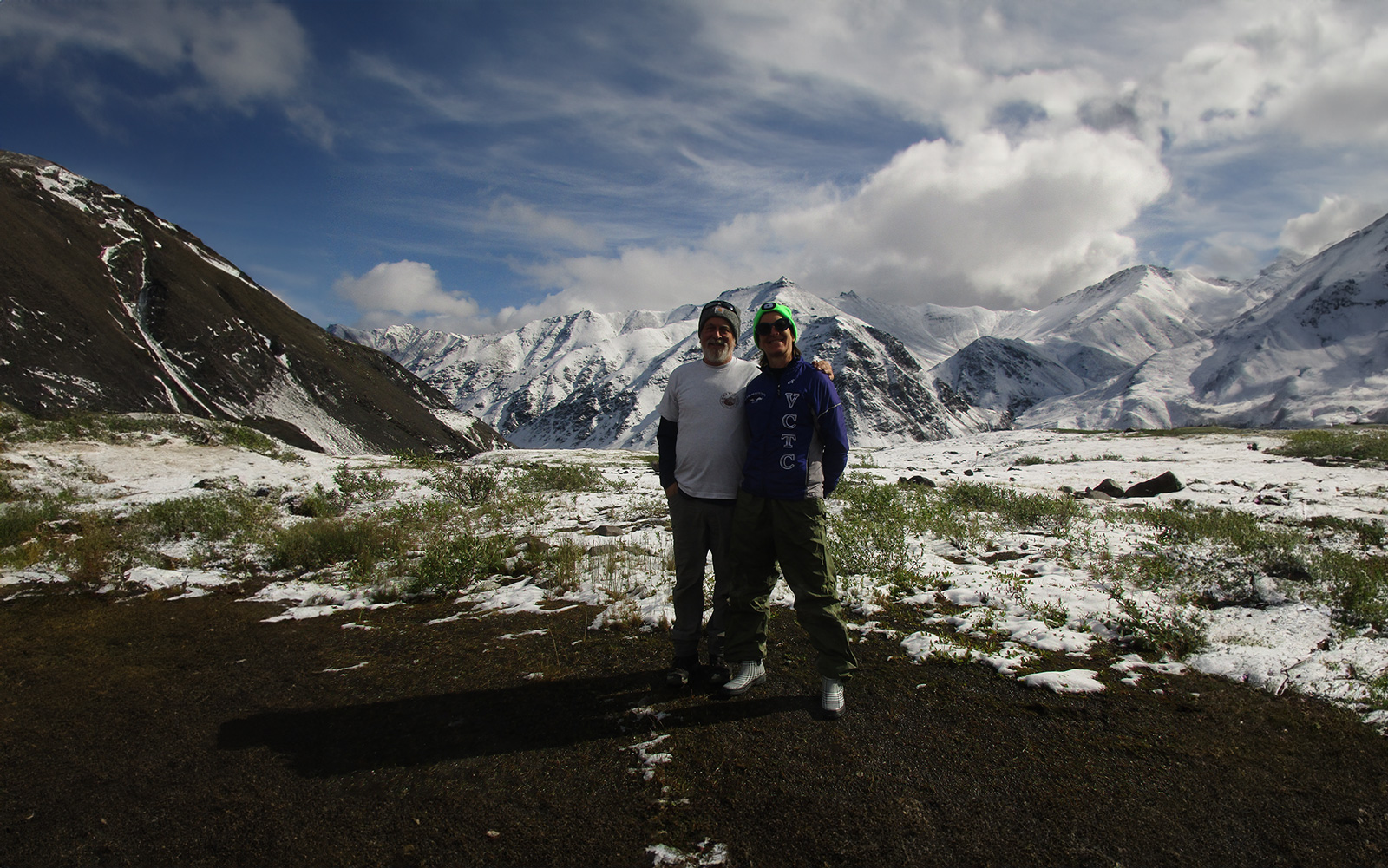 Man and woman dressed in hiking attire standing in Alaska tundra