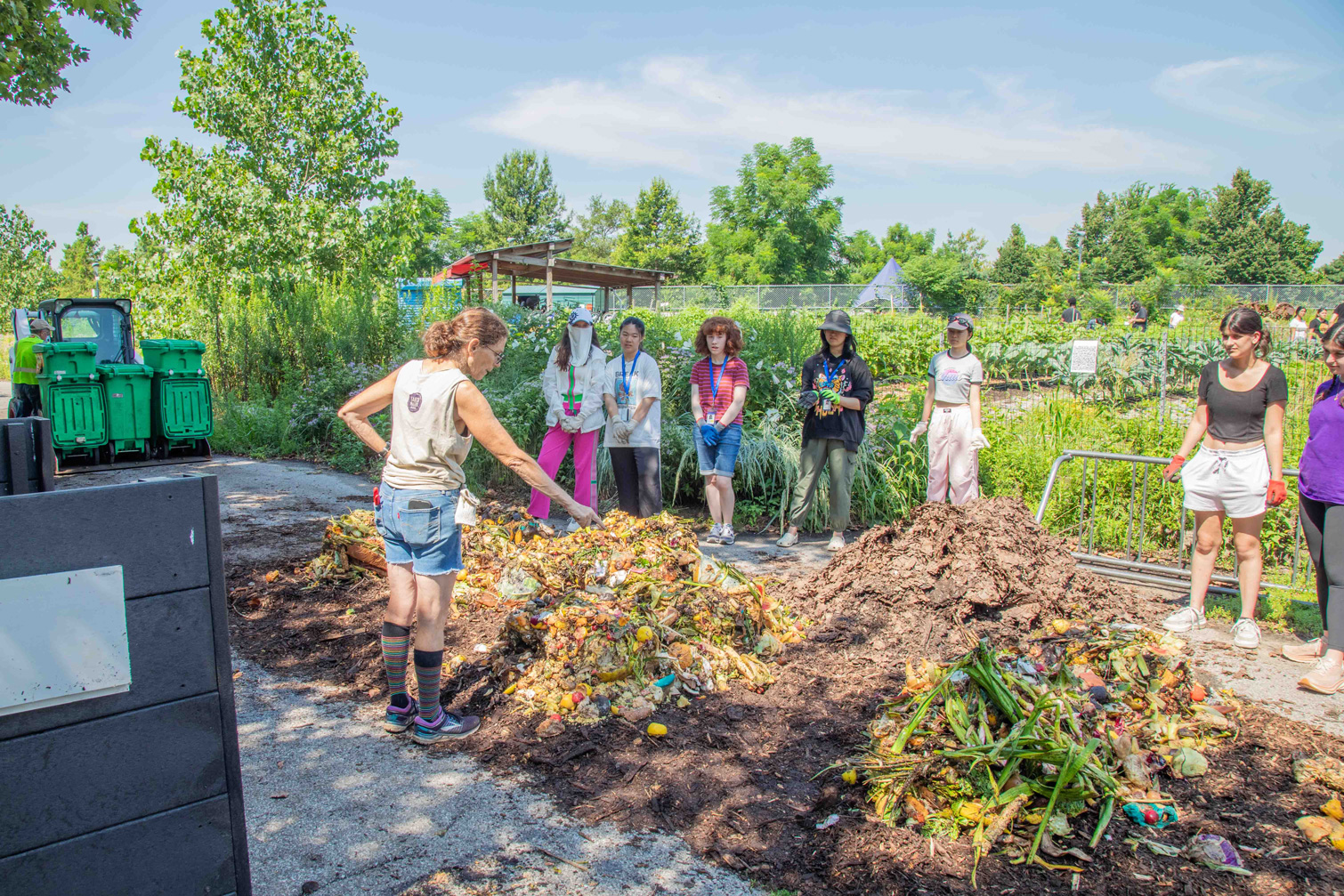 Woman and students standing in front of piles of compost