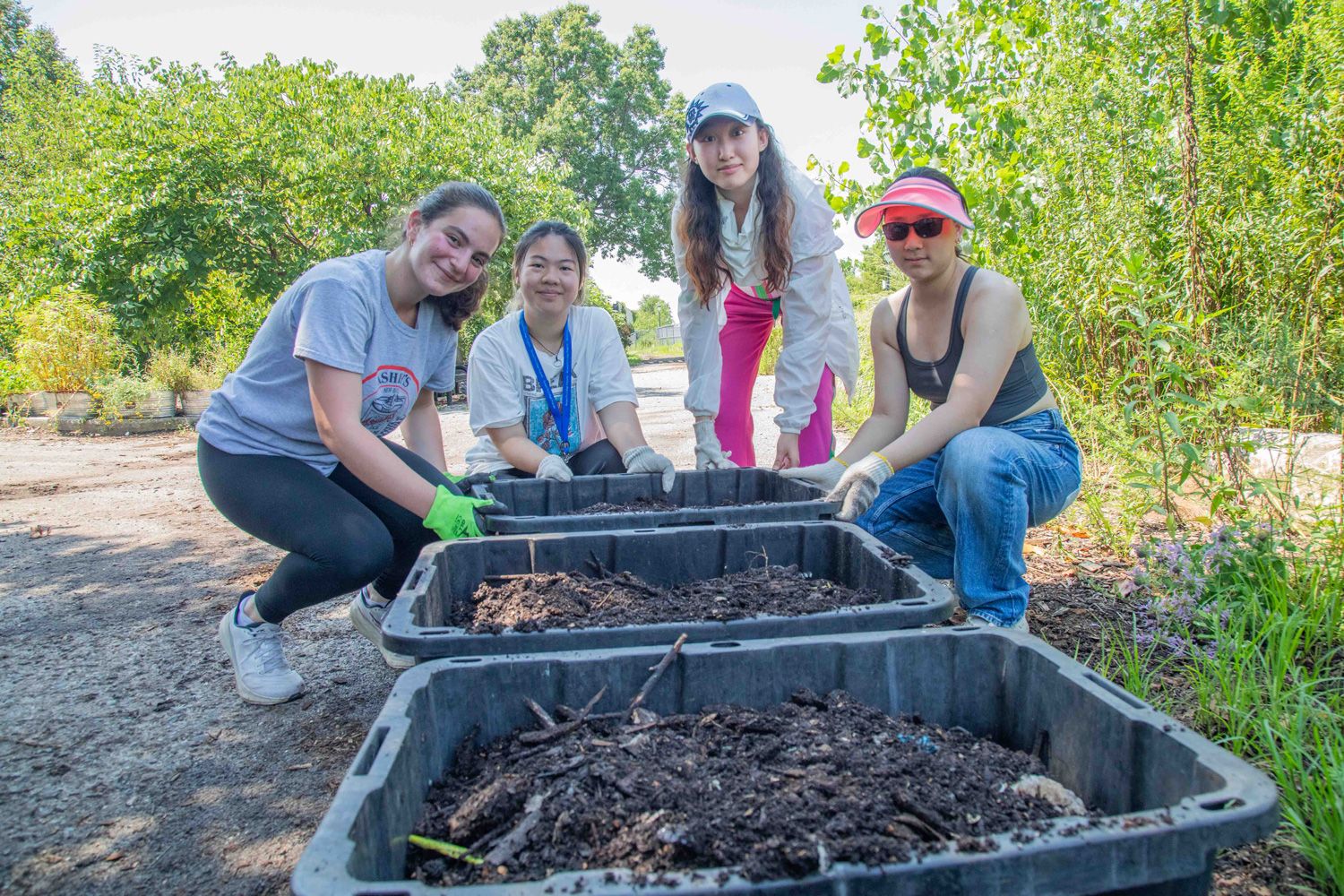 Students leaning in front of rows of dirt