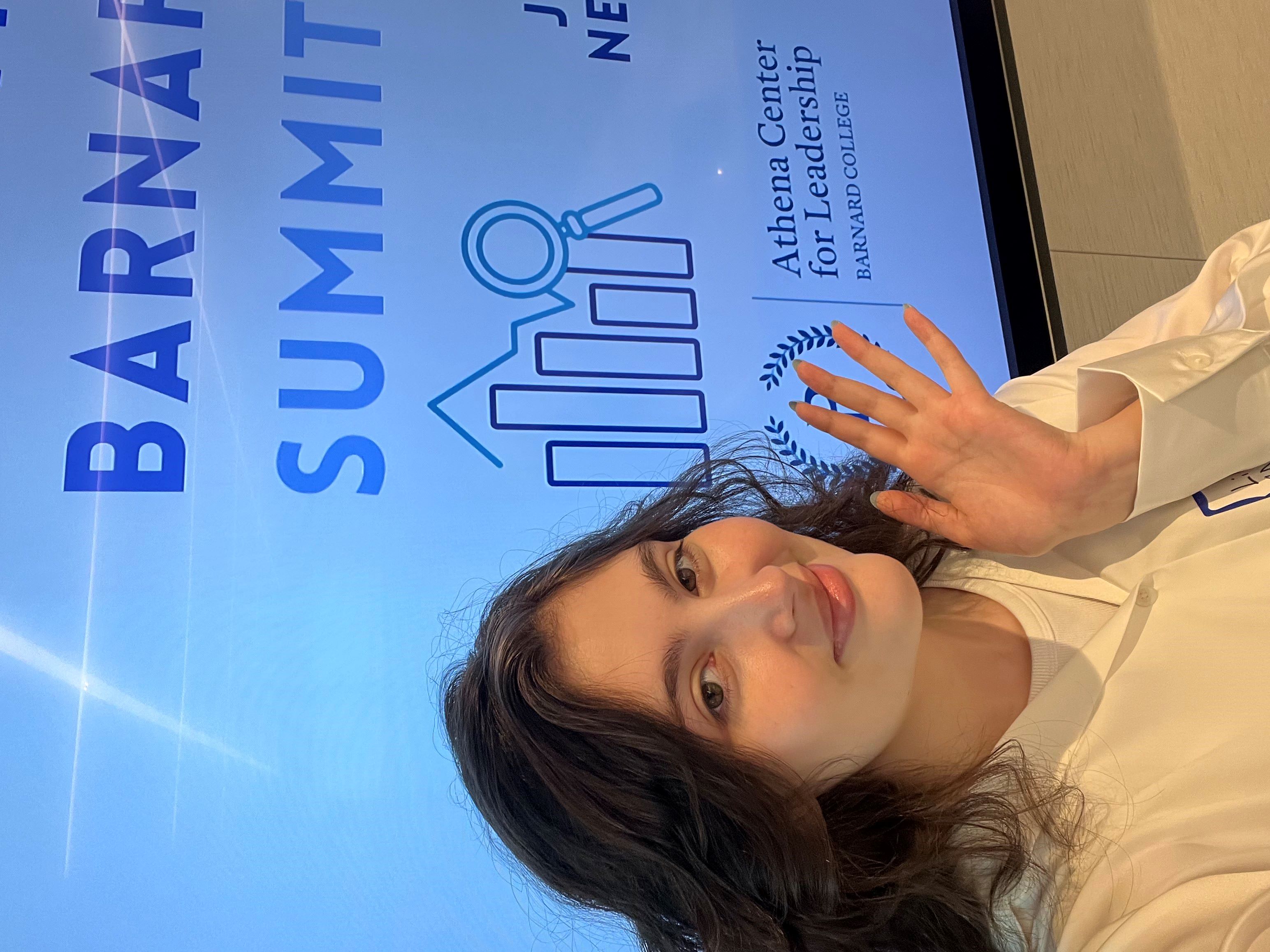 [Image description: A selfie of Athena intern Lilly Montelle '27 in front of a screen that reads "Barnard Startup Summit"]