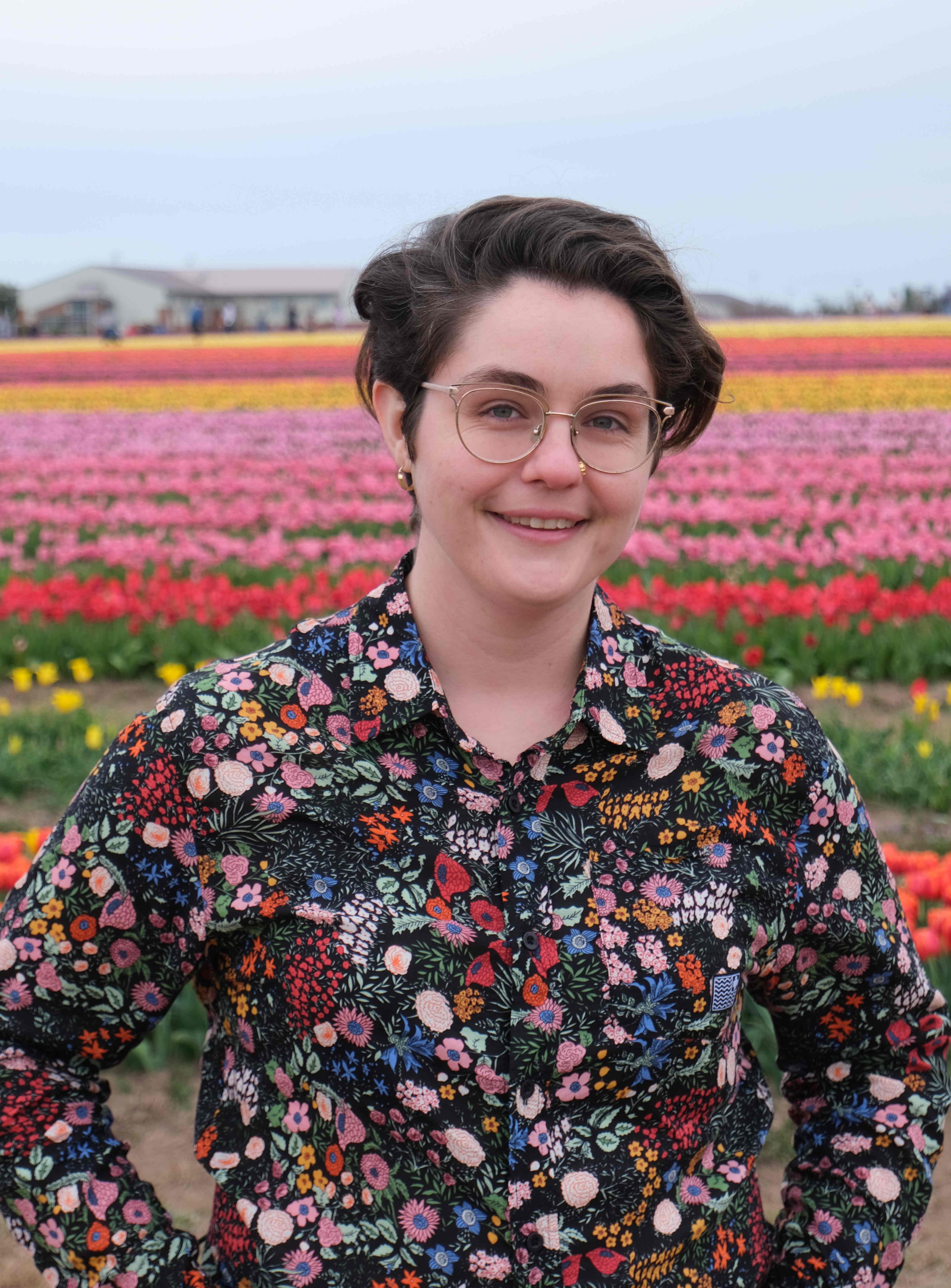 Meghan Hartman wearing a floral long sleeve shirt in a field of tulips