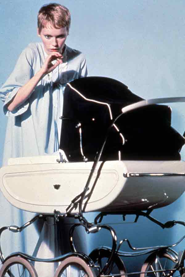 A film still of actress Mia Farrow peering into a babu carriage with a look of horror