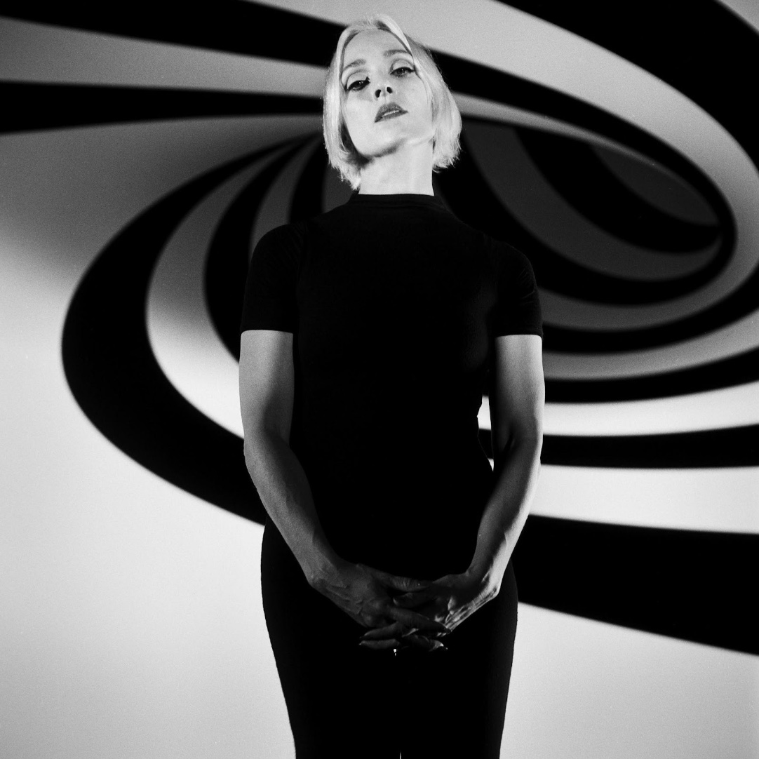 A women artist in black dress in front a black and white back ground. 