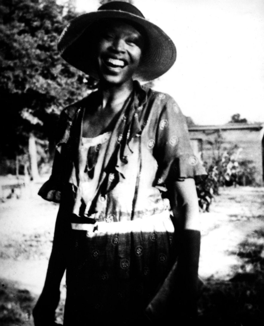 Black and white photo of woman in hat on rural land