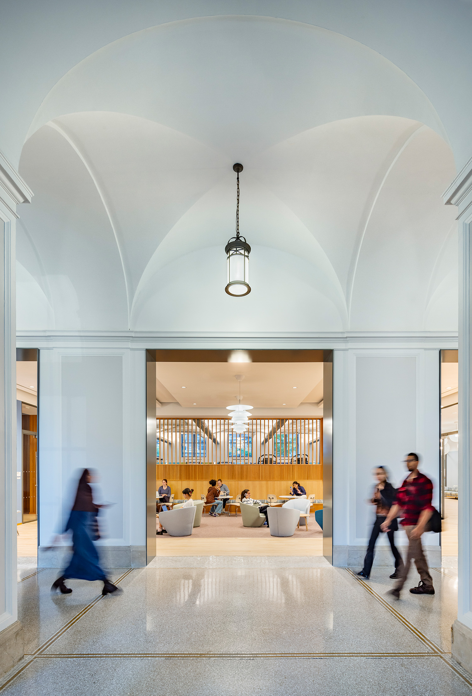 Students pass through the restored lobby. White walls and archways lead into the Lefrak center.