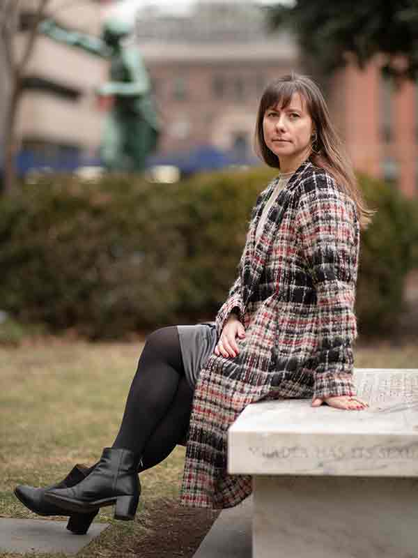 Nicole Anderson sits on marble bench