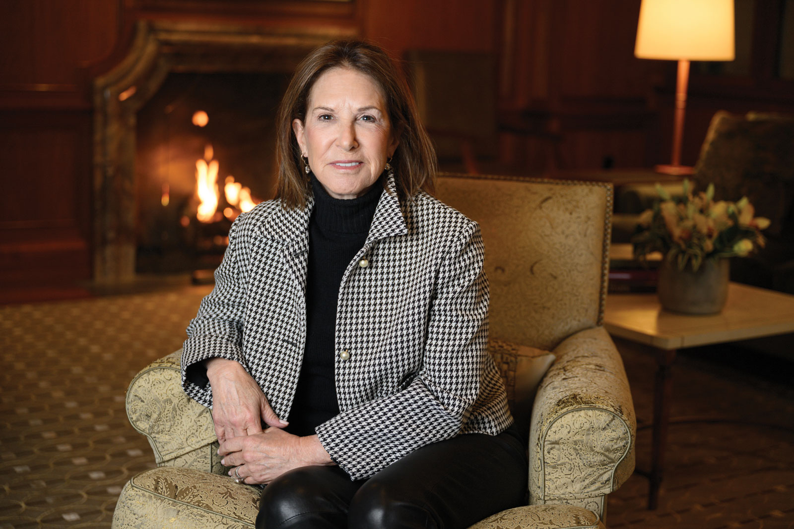 Woman wearing black and white sitting in chair in front of fireplace