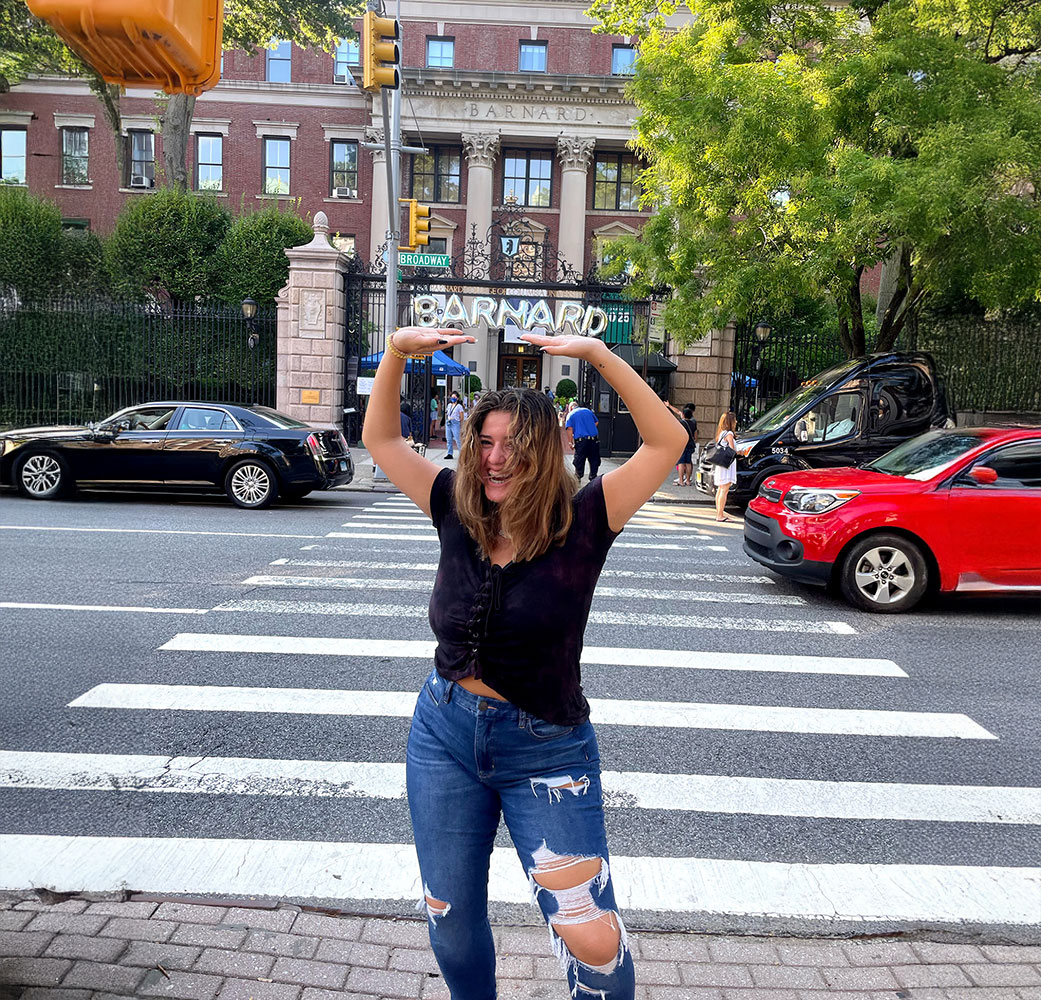 Young woman standing across street from Barnard College