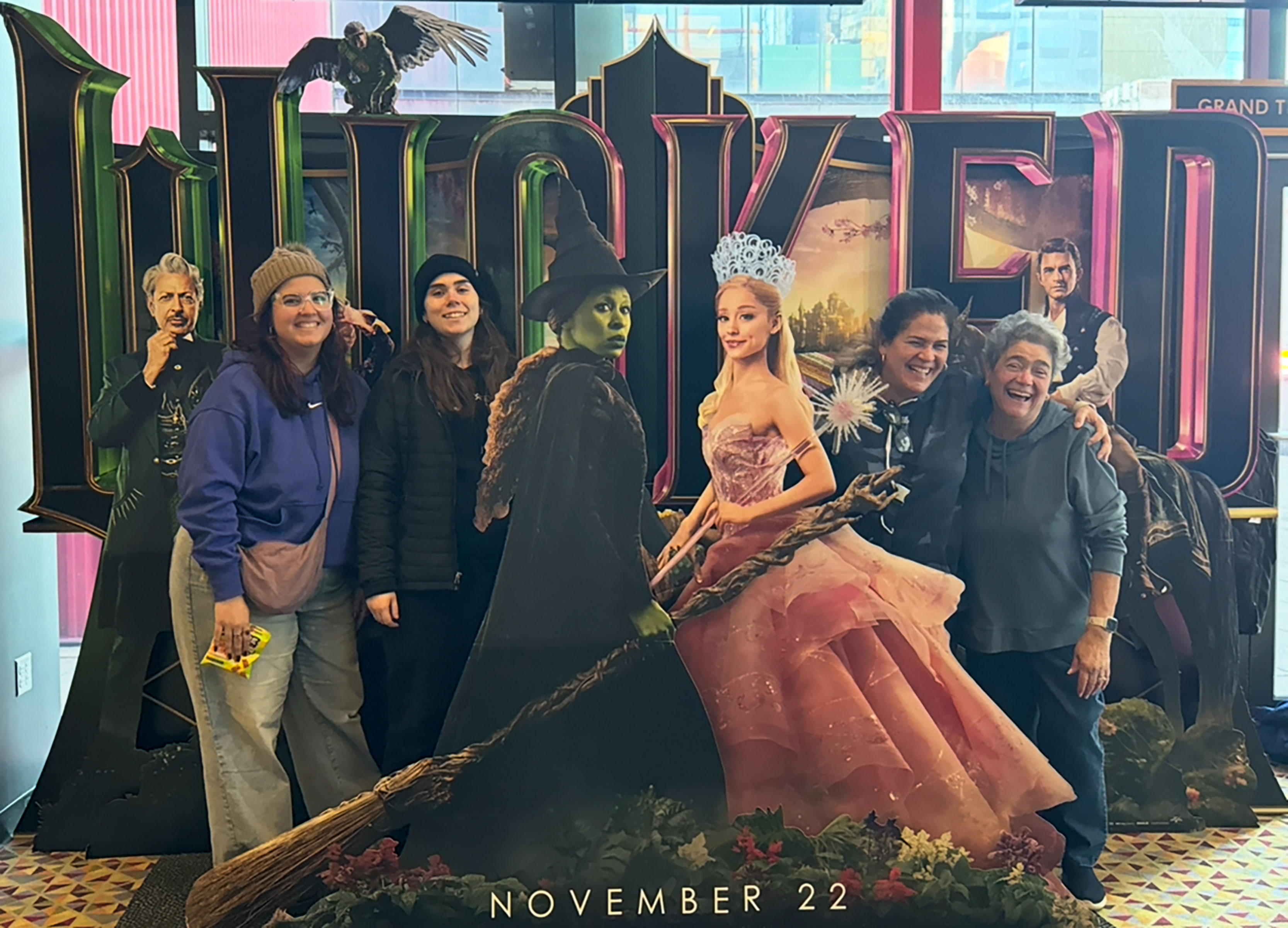 group of people posing with cutout characters from "Wicked"