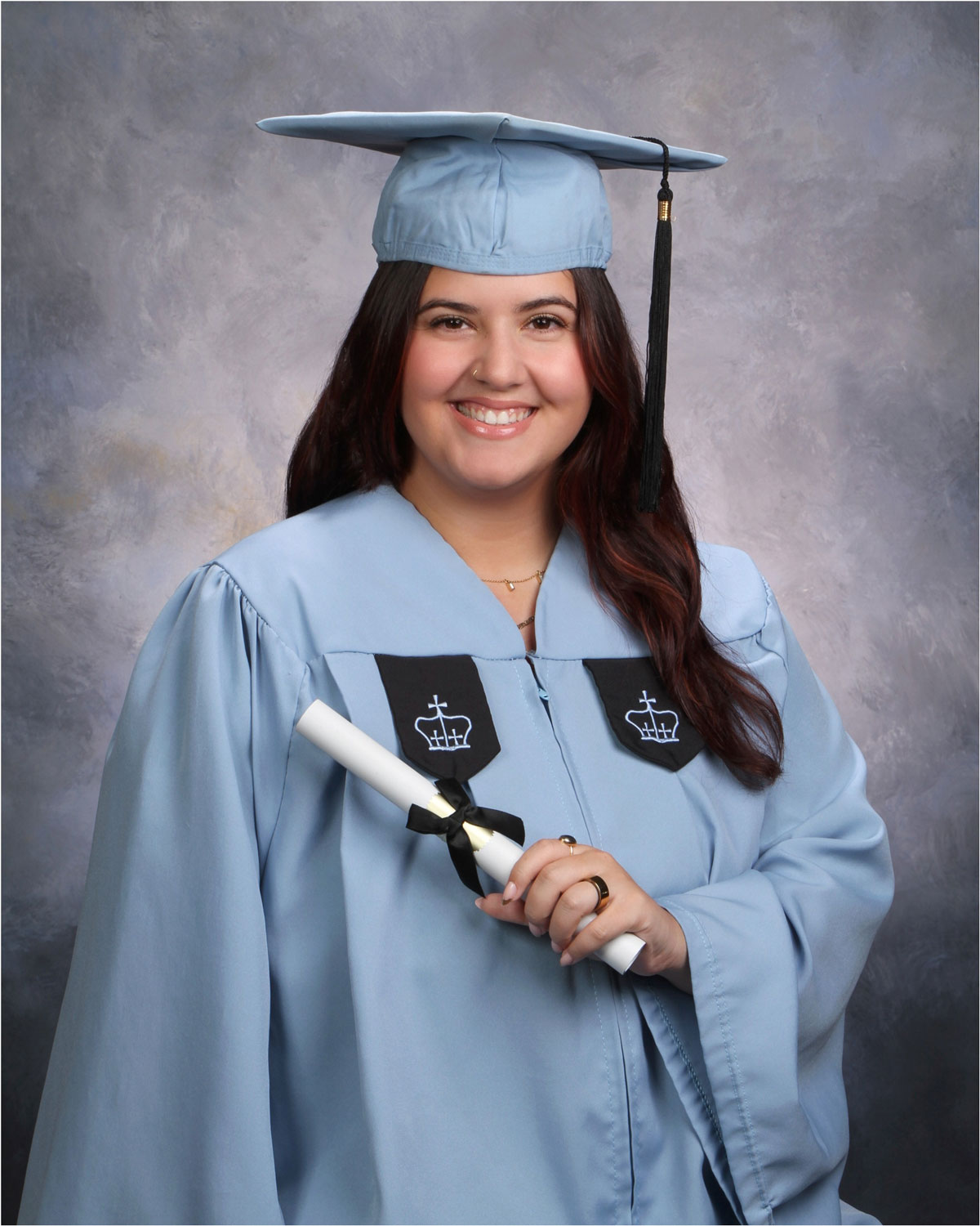 Young woman with dark hair wearing graduation cap and gown