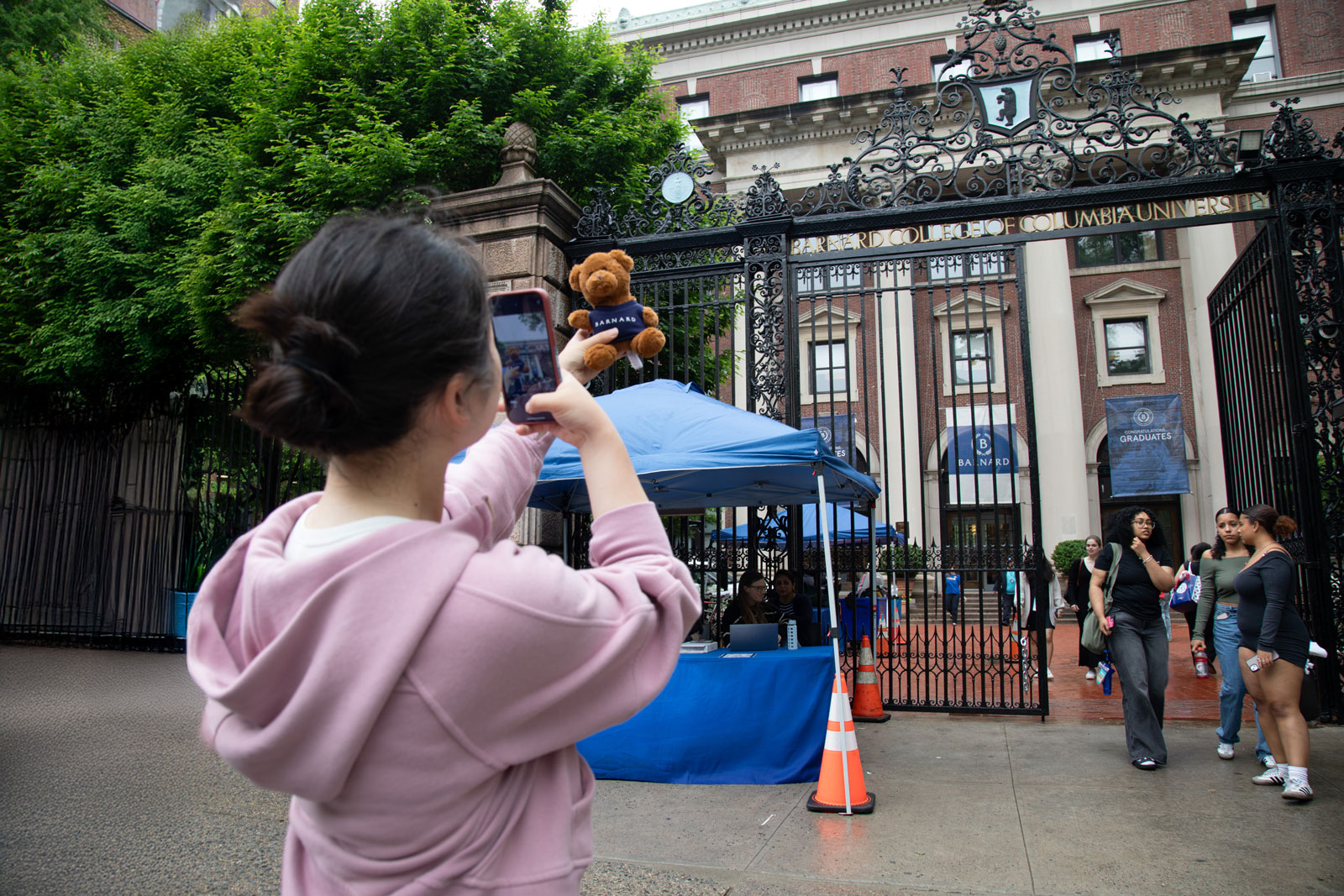 Woman standing in front of gates holding a bear