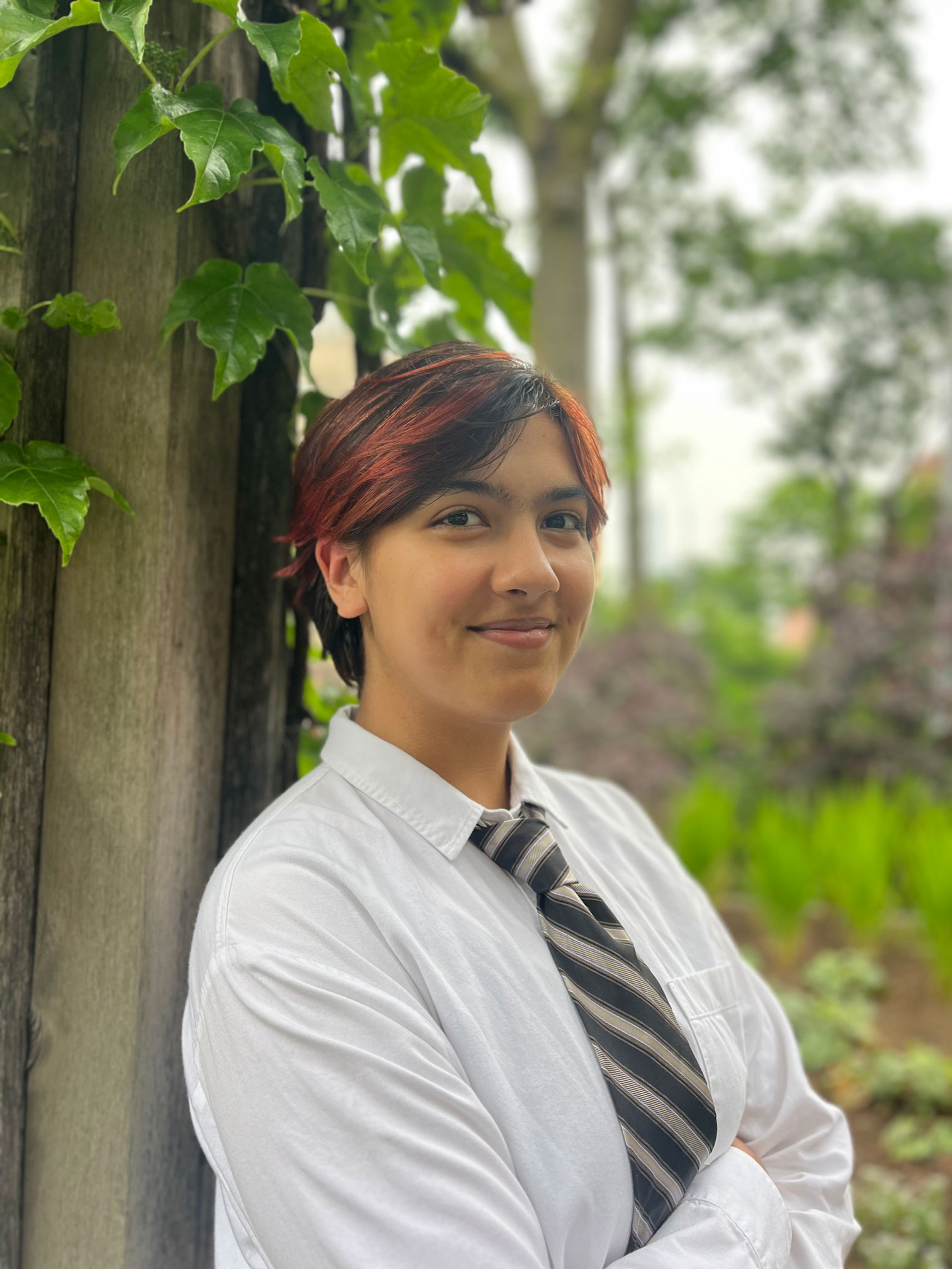 woman with short red hair leaning against a tree