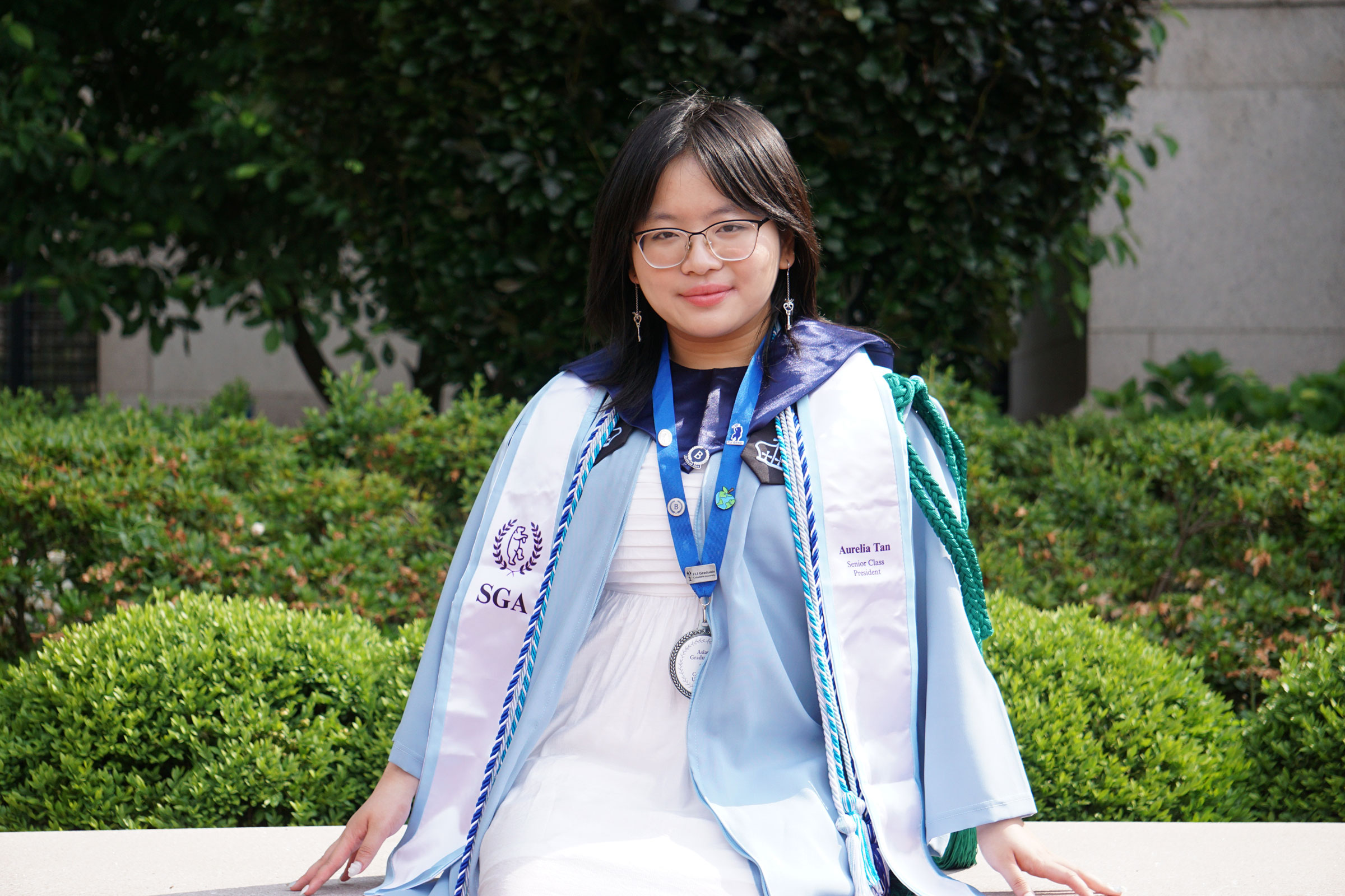 Woman with dark hair sitting wearing blue college regalia