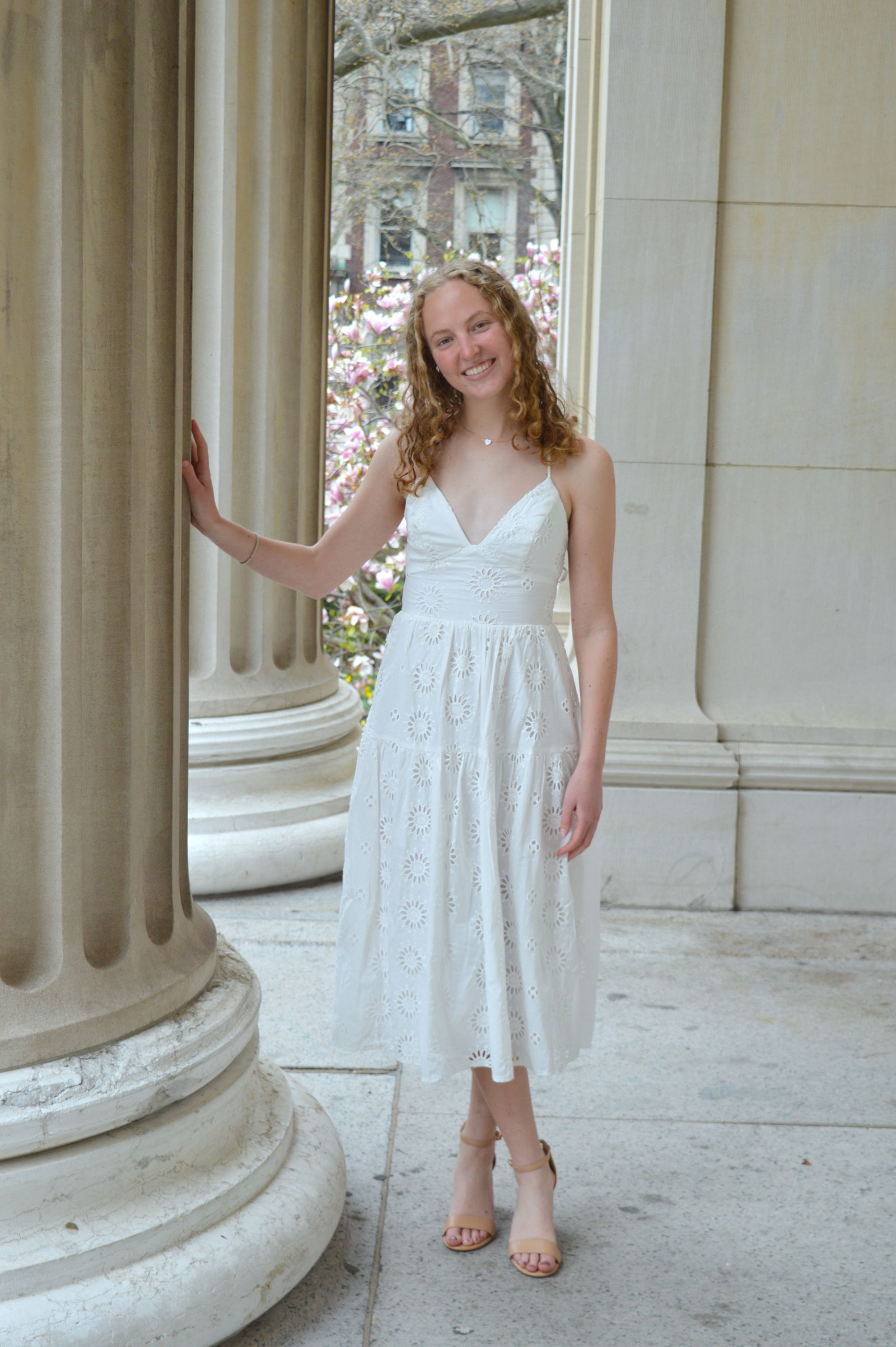 Woman standing next to pillar in white dress