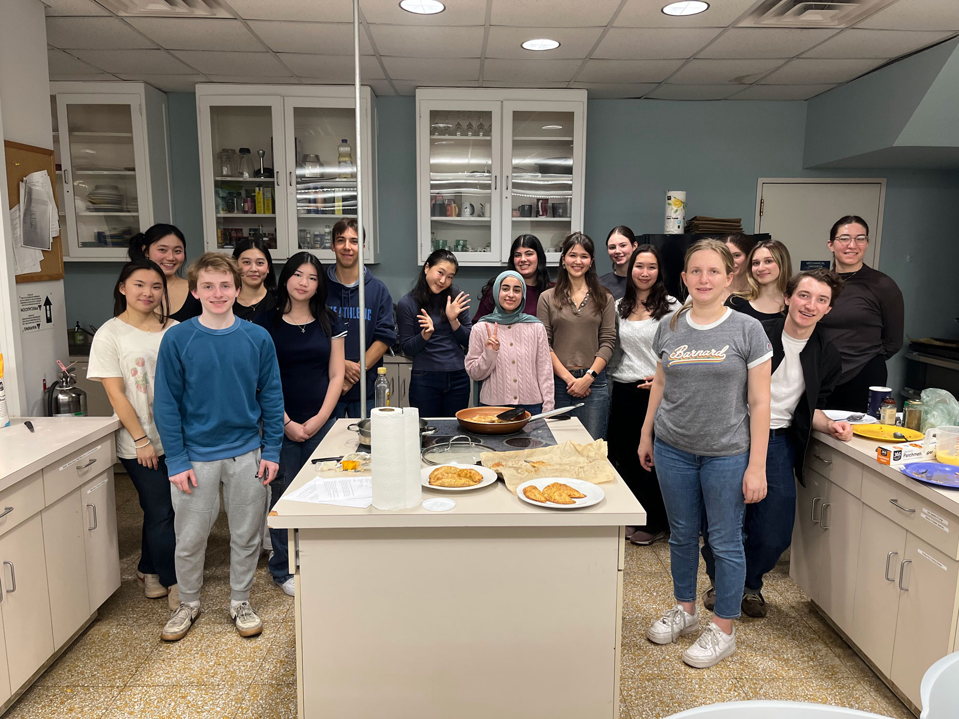 Group of students posing in kitchen near counter top and empanadas