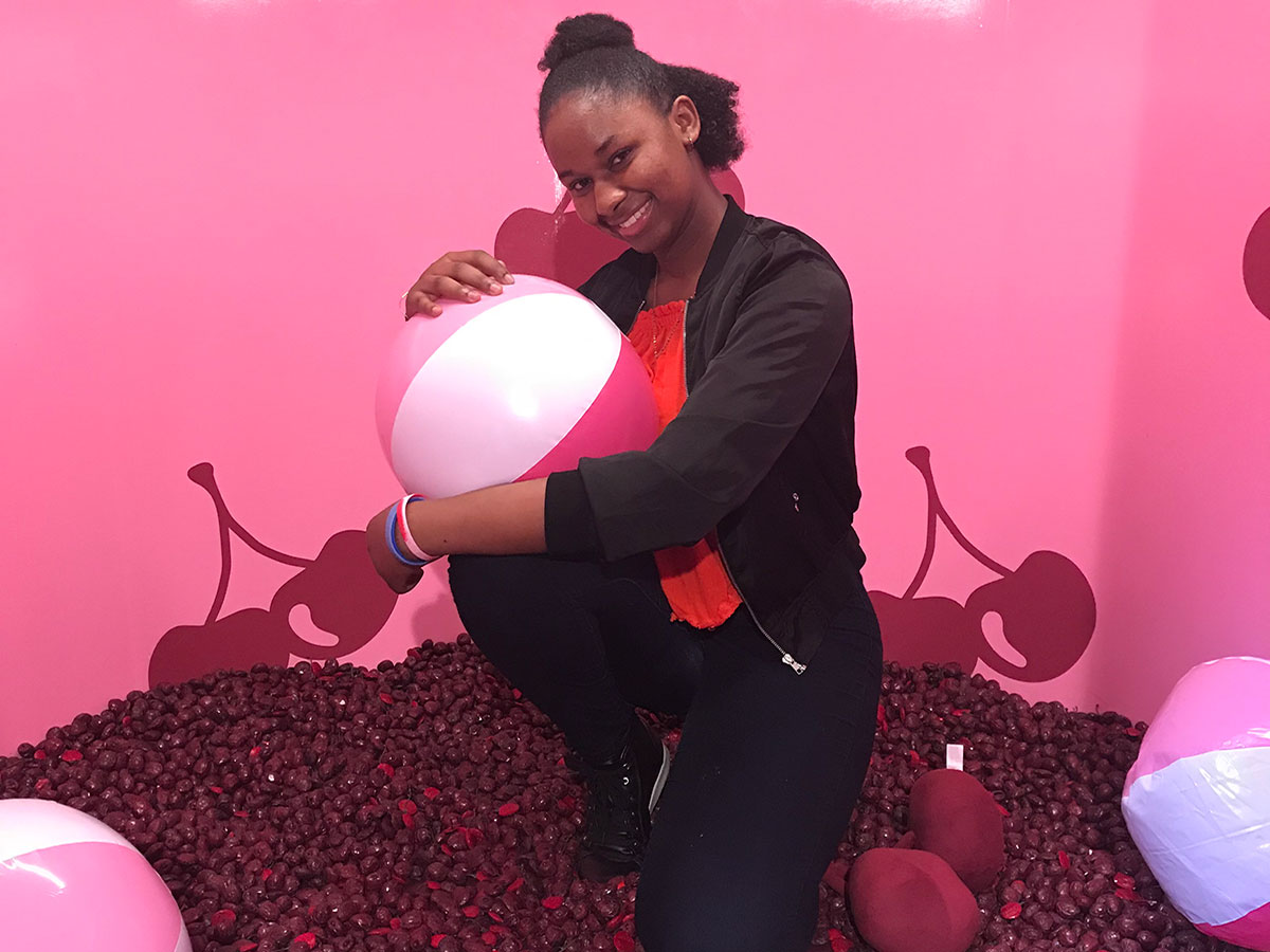 Young woman holding inflatable pink/white ball in a room with cherry wall decals.