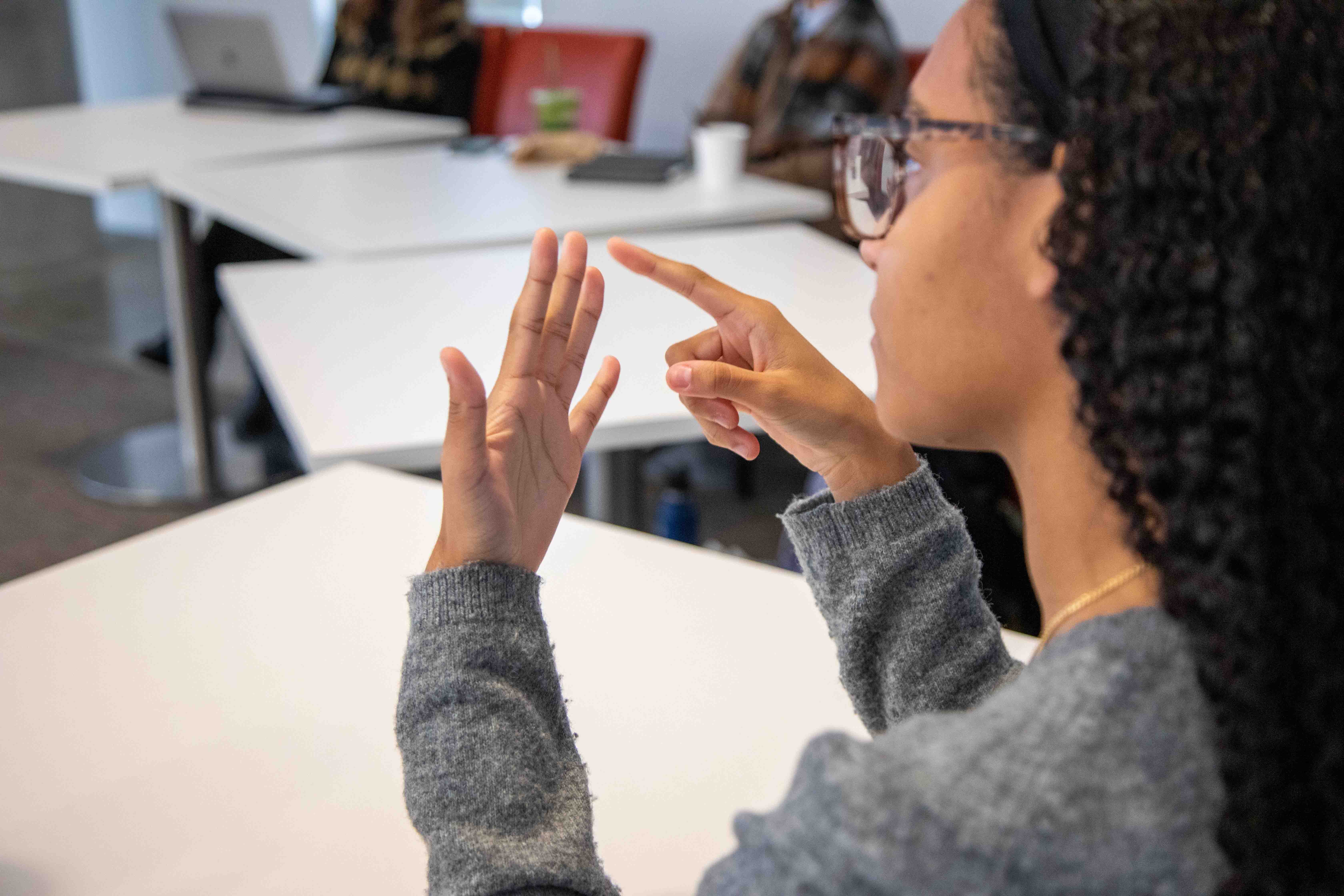 Student practicing ASL in classroom. 