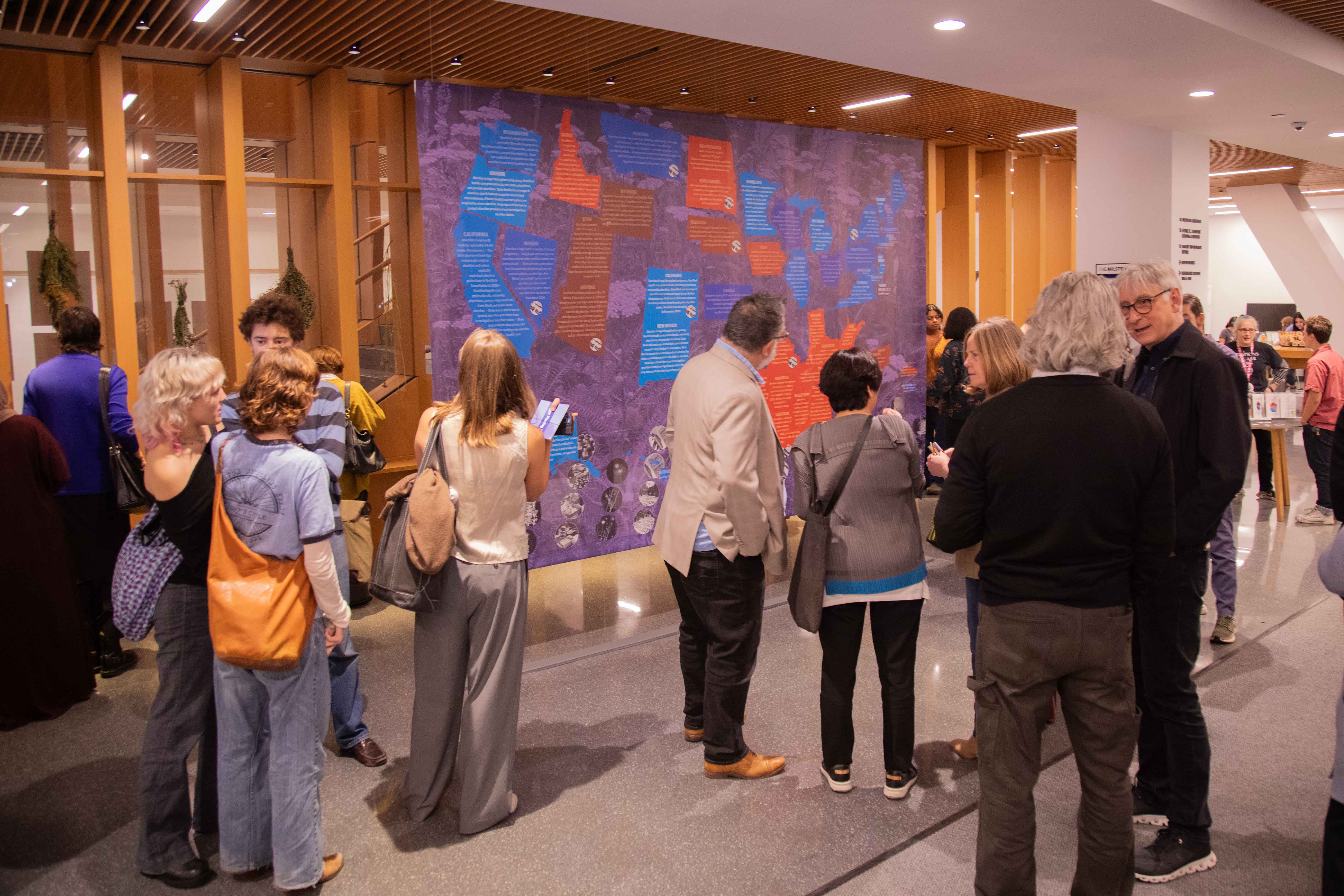 people in the milstein lobby looking at the trigger planting banner 