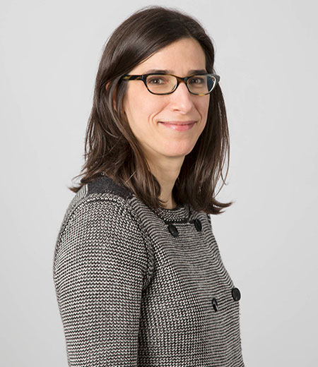 Profile of woman with dark straight hair wearing black and white jacket.