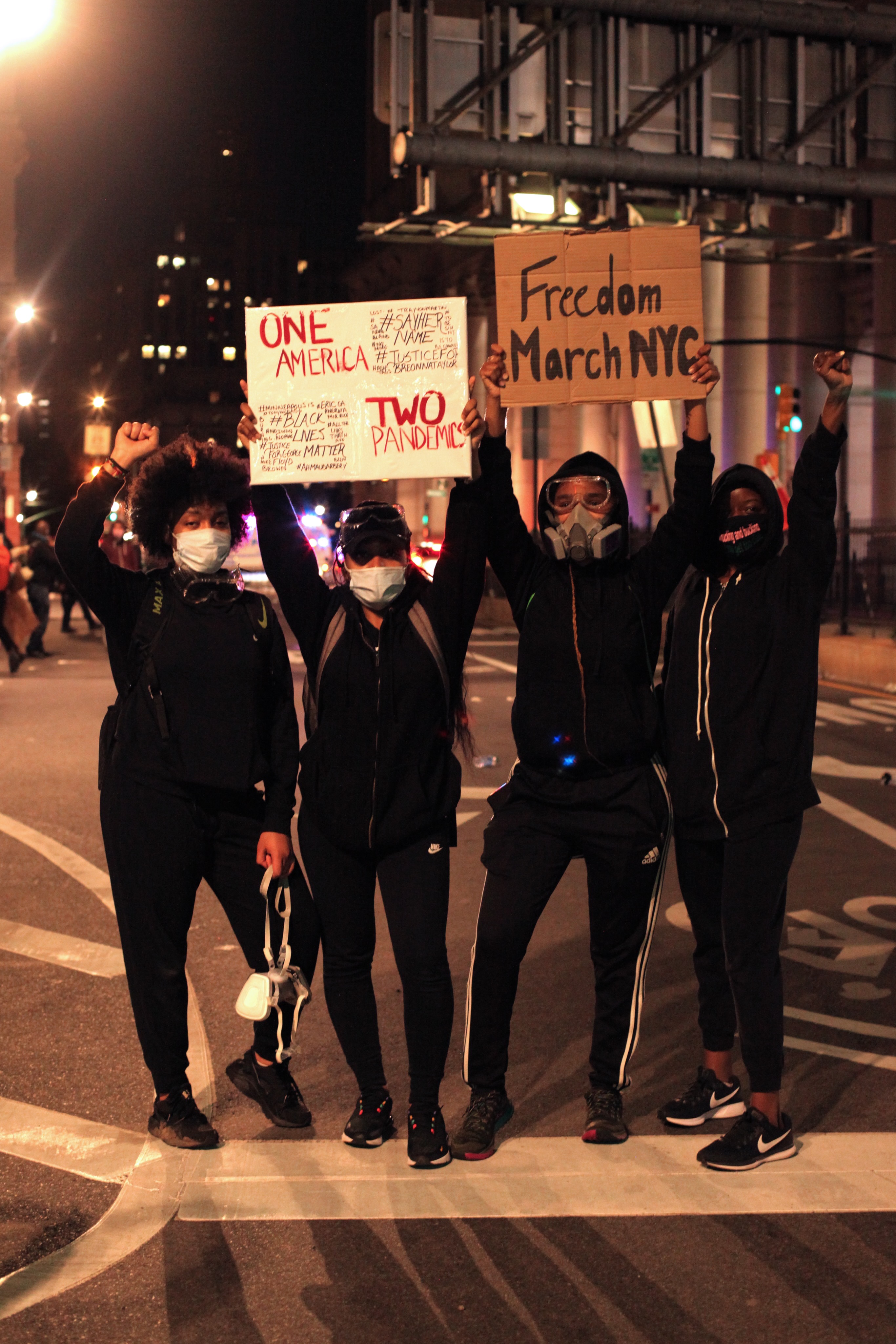 Edari and three friends holding up protest signs in the city.