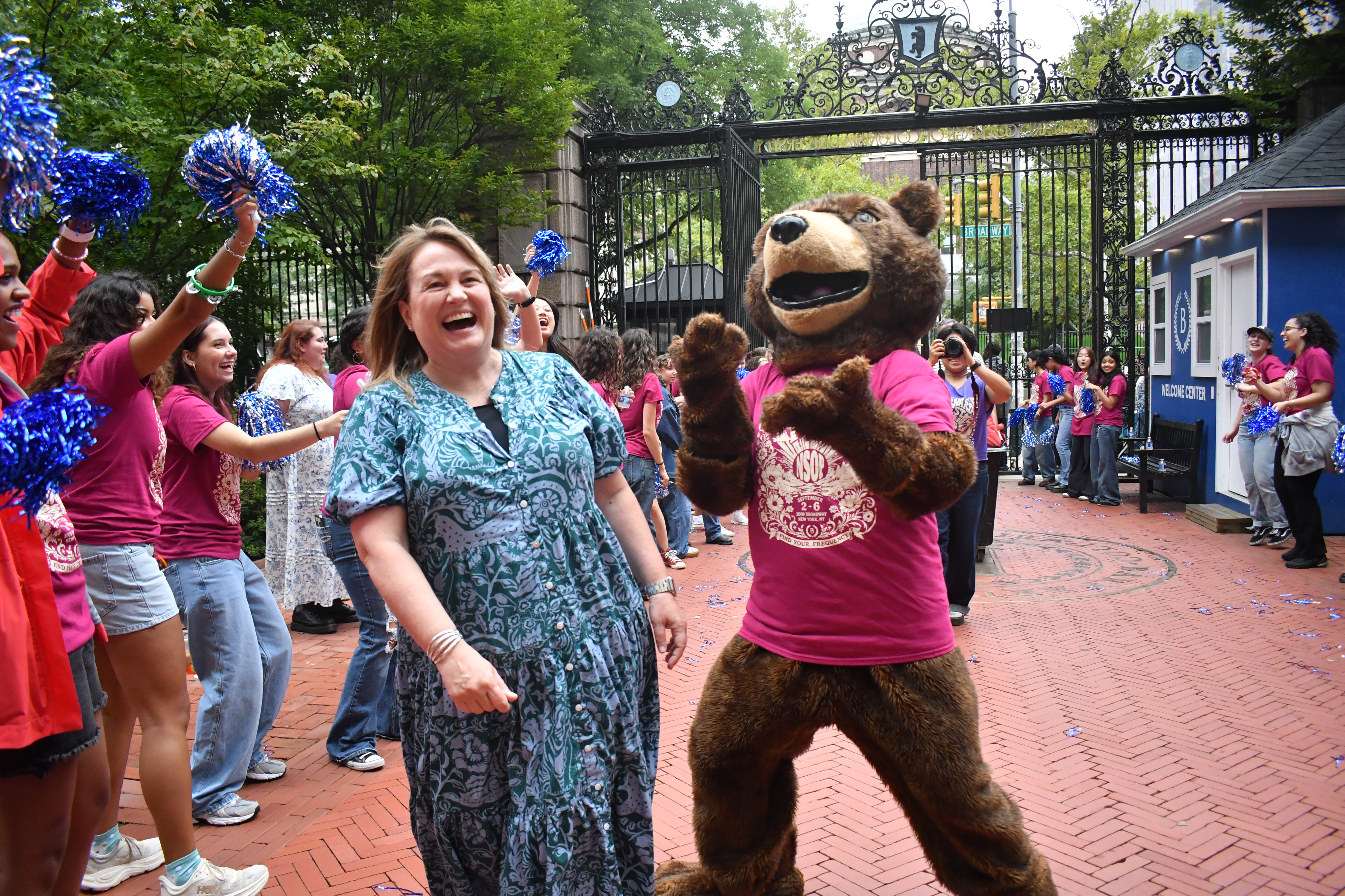 Woman smiles with bear mascot outside.