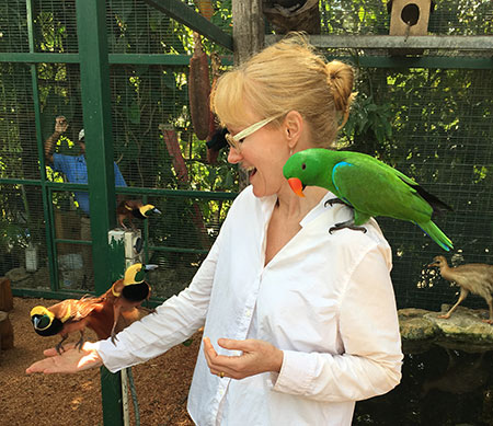 White woman with green bird on shoulder.