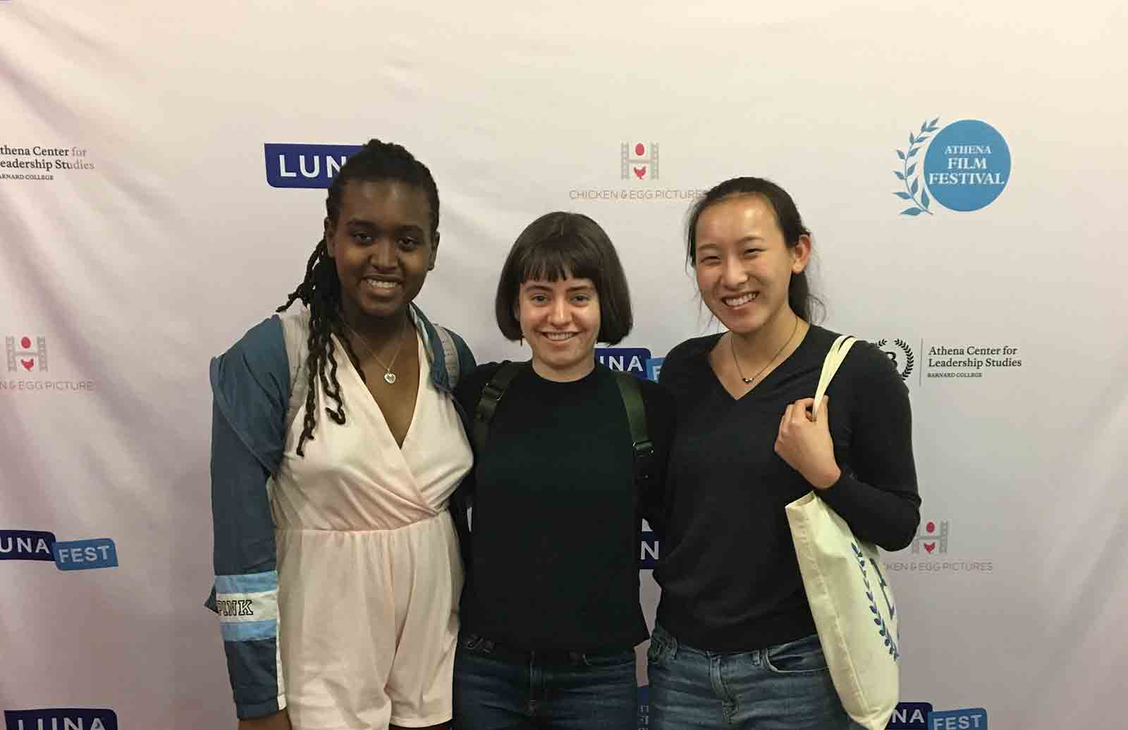 Three young women standing in front of step-and-repeat