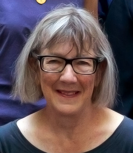 Headshot of woman with gray bob haircut, wearing blue shirt.